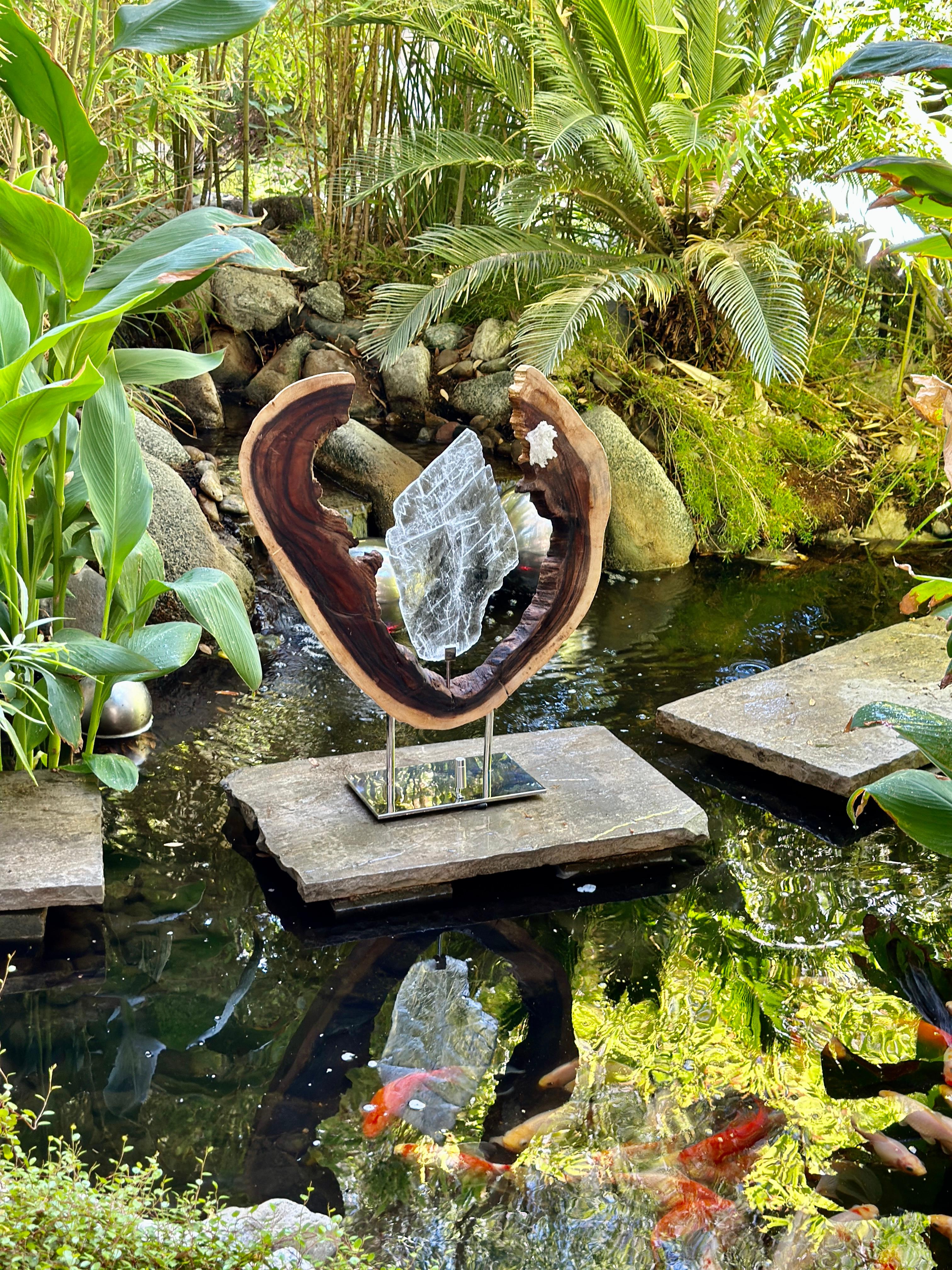 The Guardian of Love is a striking blend of Selenite, Quartz Crystal, Acacia Wood, and a steel base, illuminated with LED lights, offering not only visual beauty but also profound healing properties. The Selenite Cluster promotes mental clarity and