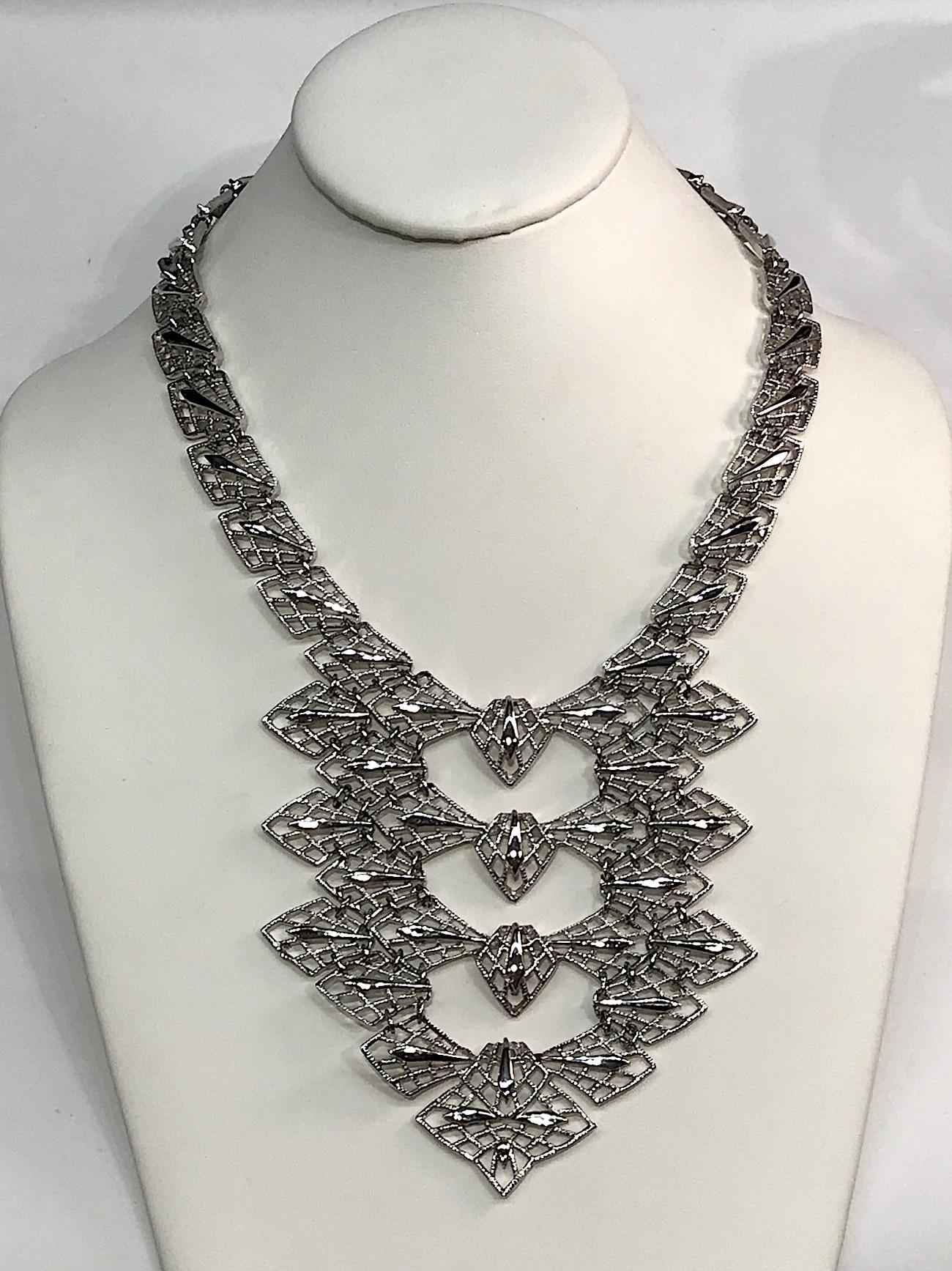 A wonderful sculptural abstract statement necklace by the company D'Orlan and from the 1970s. The necklace is comprised of silver tone diamond shape openwork pieces. They are connected with small round rings to create a 4 inch by 4 inch from bib.