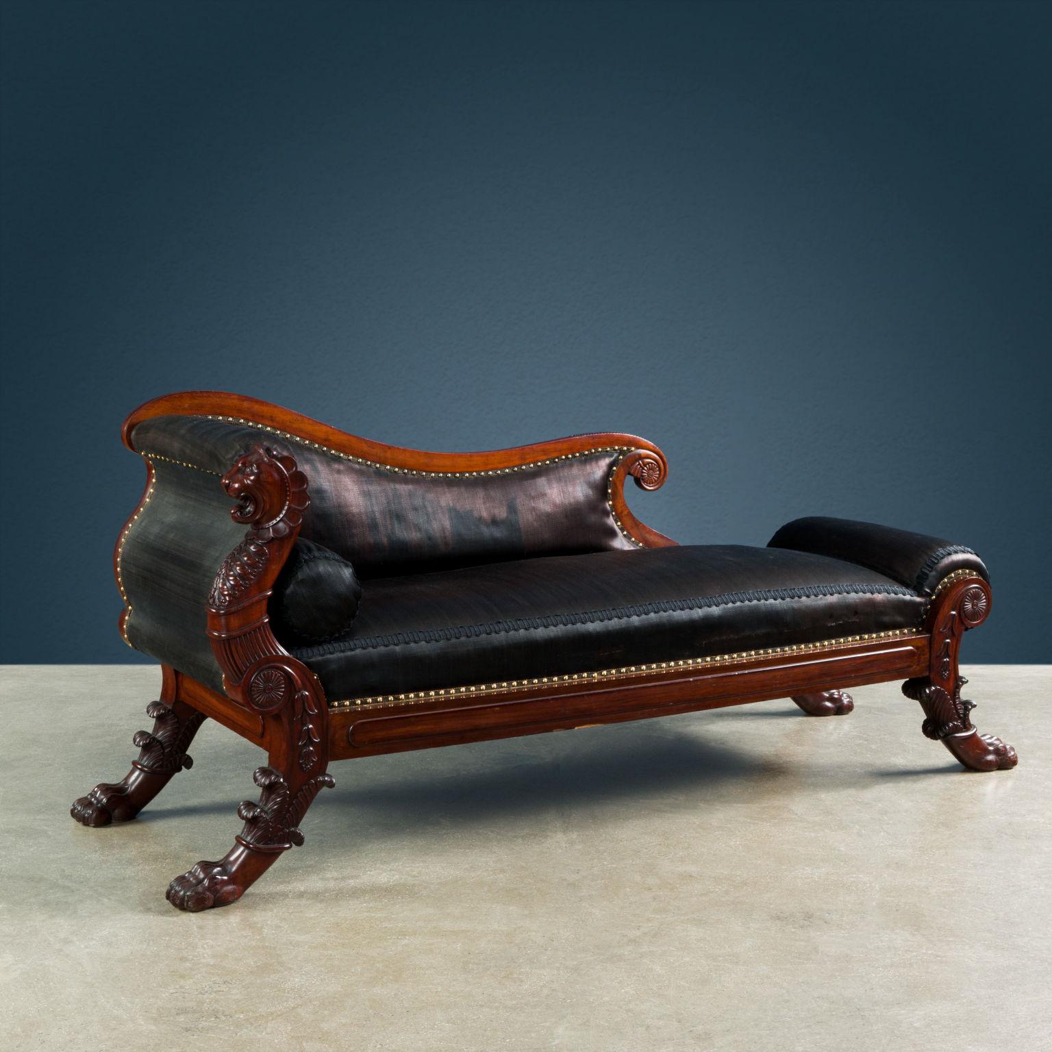 Center triclinium sofa, made of mahogany and upholstered in black horsehair fabric. The saber feet are carved in the form of a lion's paw swathed in acanthus leaves from which sprouts a volute decorated with rosettes and bellflowers; the front