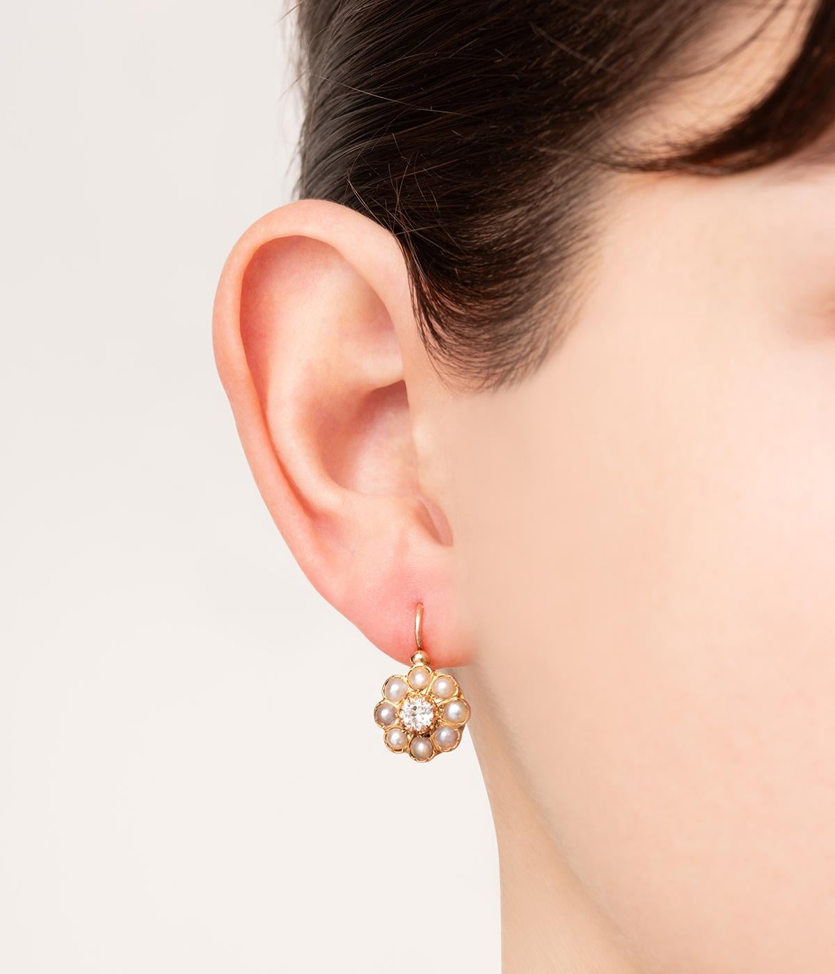 Dormeuses anciennes en or rose et jaune 18 carats (750 millièmes) de la seconde moitié du 19ème siècle, en forme de fleur soulignées de perles fines et centrées chacune d'un diamant taille brillant pensant 0,20 carat.

Poids total du bijou : 4 g