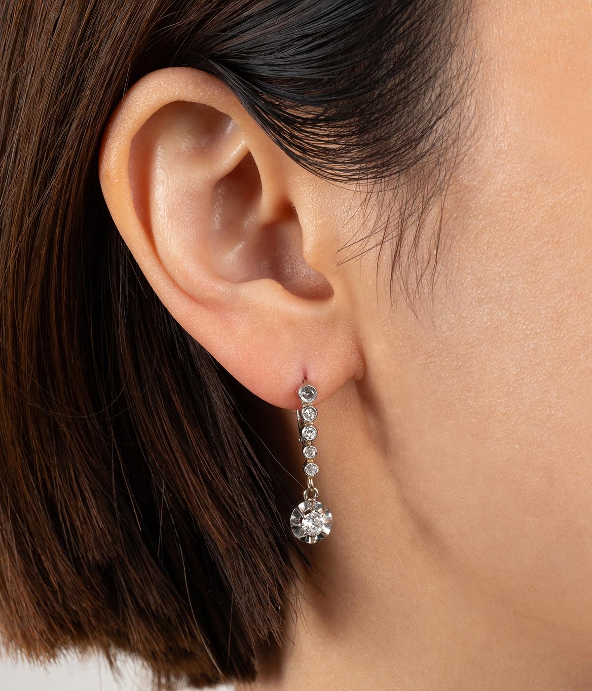 Dormeuses anciennes en or 18 carats (750 millièmes) et platine du début du 20ème siècle, composées d'une ligne de diamants taille 8/8 en chute et sertis millegrain, retenant en pampille un diamant taille ancienne d'env. 0,20 carati in serti