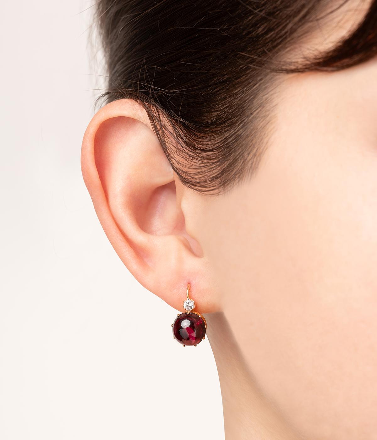 Dormeuses anciennes en or rose 18 carats (750 millièmes) du milieu du 19ème siècle ornées d'un cabochon de grenat d'env. 3,10 carats chacun surmontés d'un diamant taille brillant de 0,1 carat environ.

Poids total du bijou : 2,95 g.
Hauteur 1,5