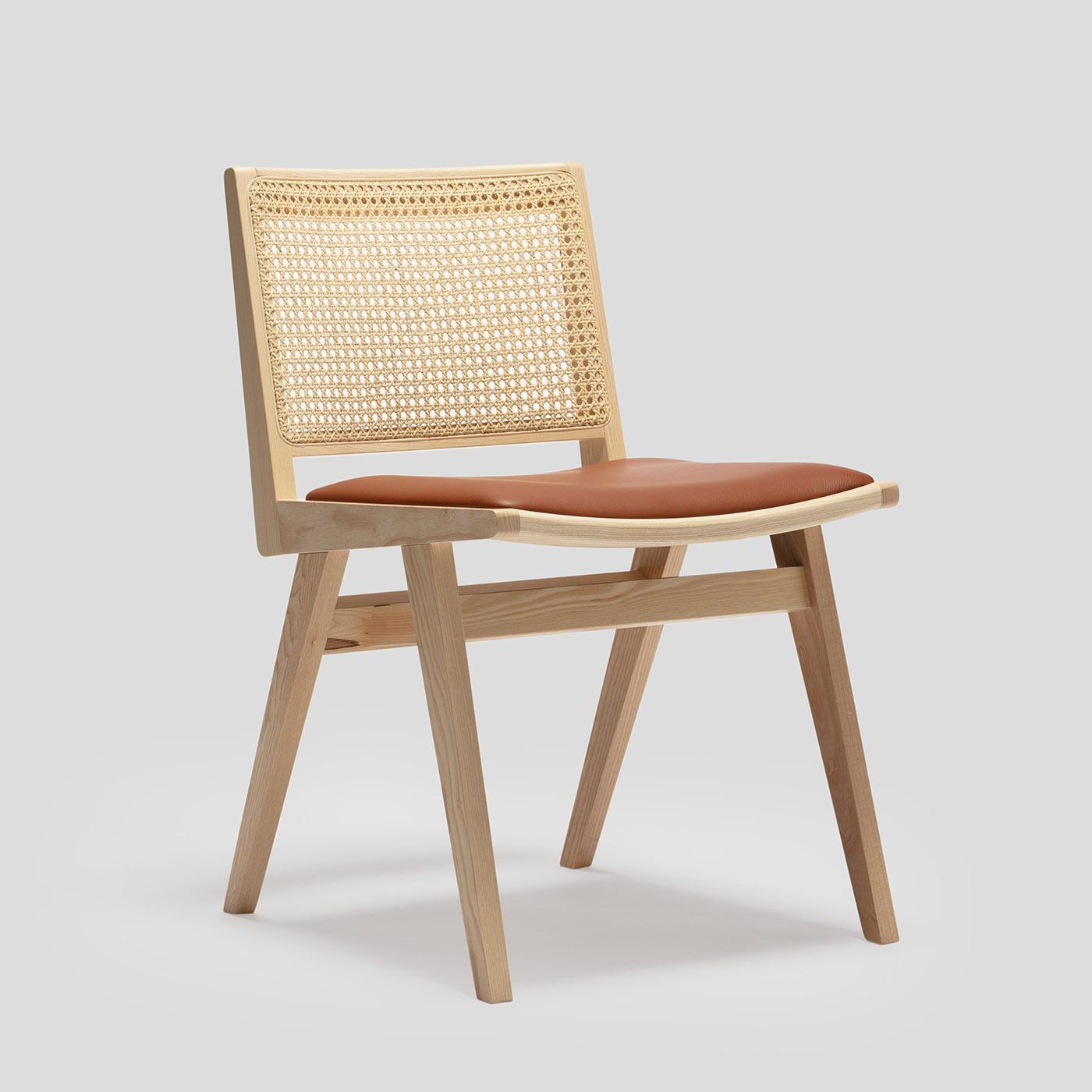 La nuova sedia Dorothea combina un design essenziale con l'iconica onda di canna. L'intera famiglia è composta da una sedia, una poltrona e uno sgabello, realizzati in legno di frassino con uno schienale in canna all'interno di una struttura in