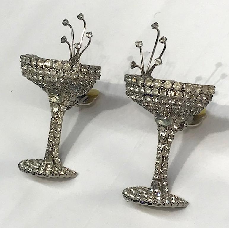 A large and rare pair of 1980s Dorothy Bauer rhinestone champagne glass earrings. Each earring measures 1.5 inches wide, 2.63 high and 1 inch deep not including the clip back. The earrings are rhodium plate and covered with round rhinestones on the