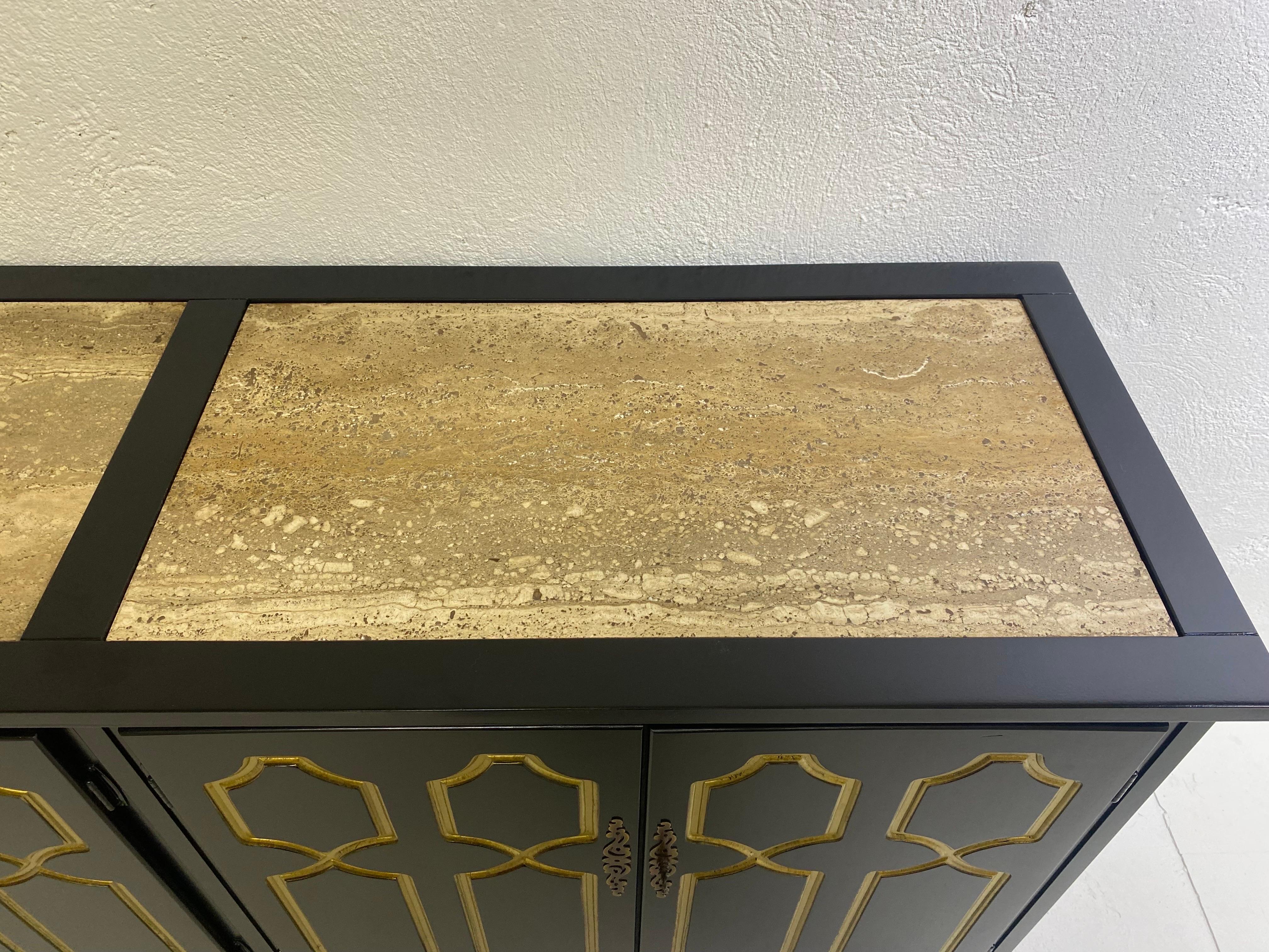 This is a black and gold Hollywood Regency Lacquered Chest buy Henredon and design by Dorothy Draper in the mid-1950s. This credenza has a natural Italian travertine inserted marble top. The credenza has an indented goldleaf design at the front of