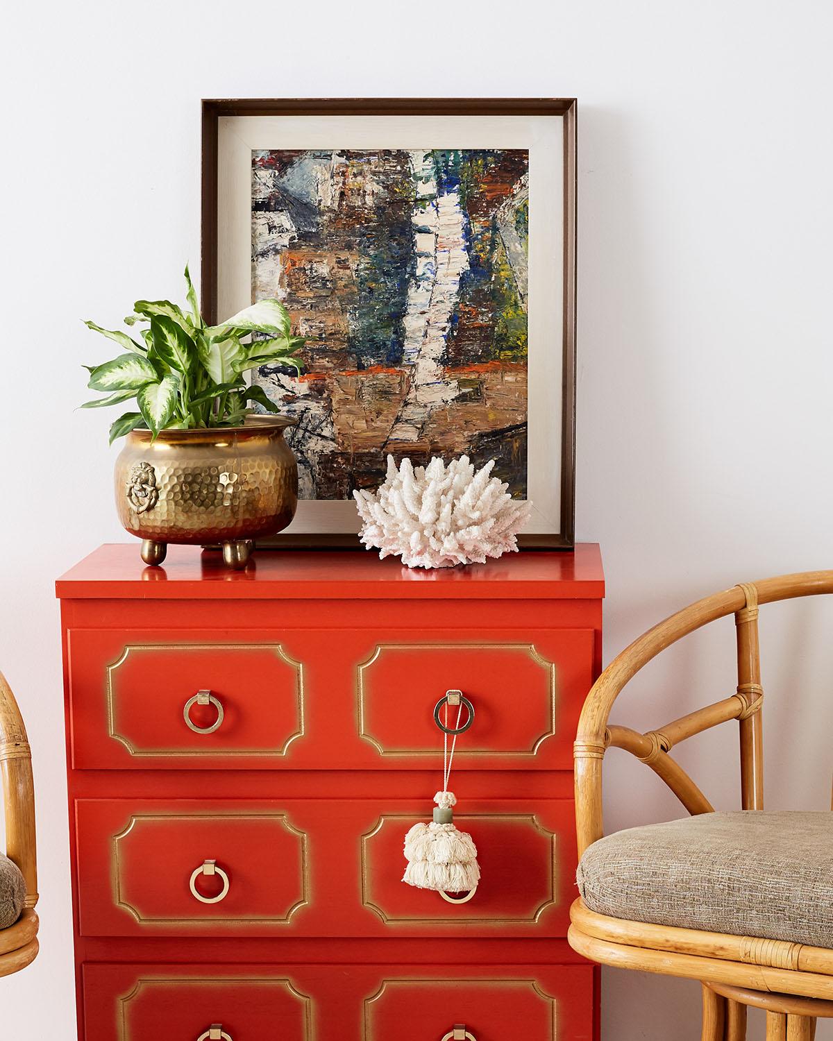 Colorful Dorothy Draper style commode or chest of drawers featuring a chic coral red lacquer with partial gilt accents. Fronted by three large drawers with brass toned pulls. Made in the mid-20th century with excellent joinery.