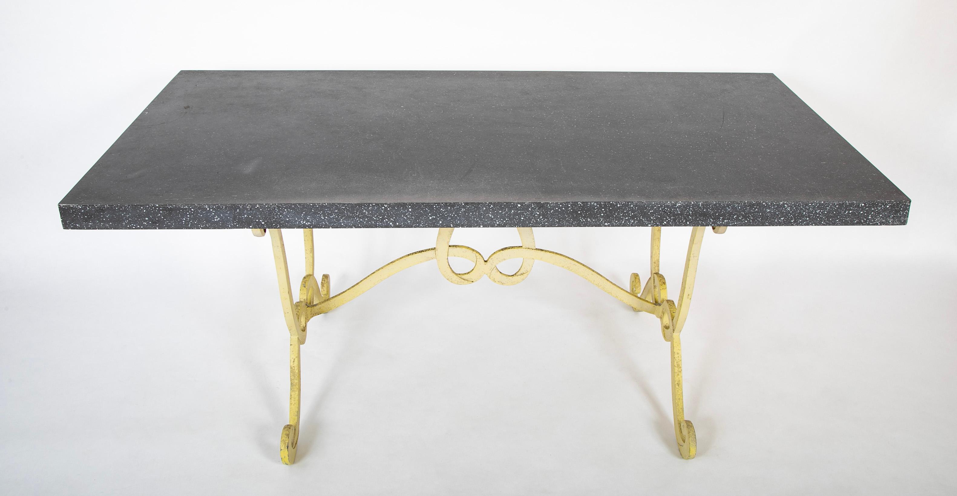 Table rare, inhabituelle et peut-être unique attribuée à Dorothy Draper. Le plateau en acier est peint en faux porphyre noir, la magnifique base en fer forgé est d'un jaune pâle. Peinture d'origine. La base évoque Apt, avec ses élégantes arabesques
