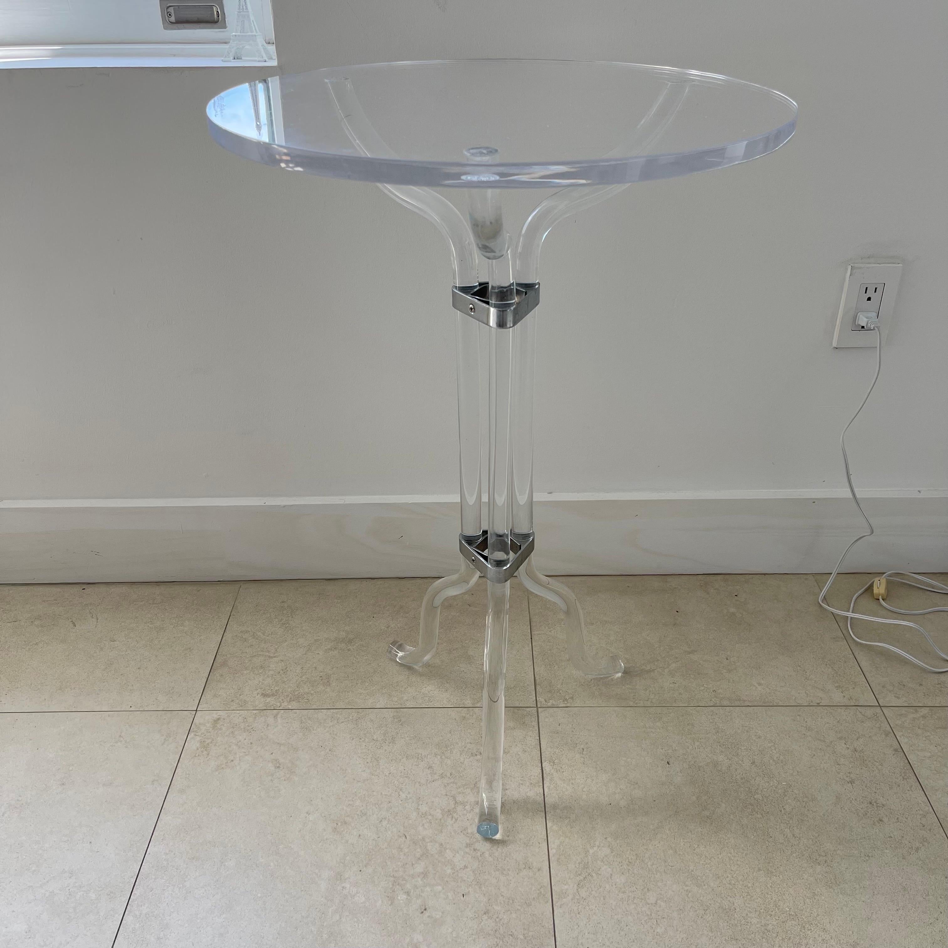 Versatile round side or end table rendered in bent lucite and chrome plated brass, iconic bent tubular lucite legs fastened with chrome plated brass banding and an affixed thick round lucite top. Attributed to Dorothy Thorpe, Made in USA, circa