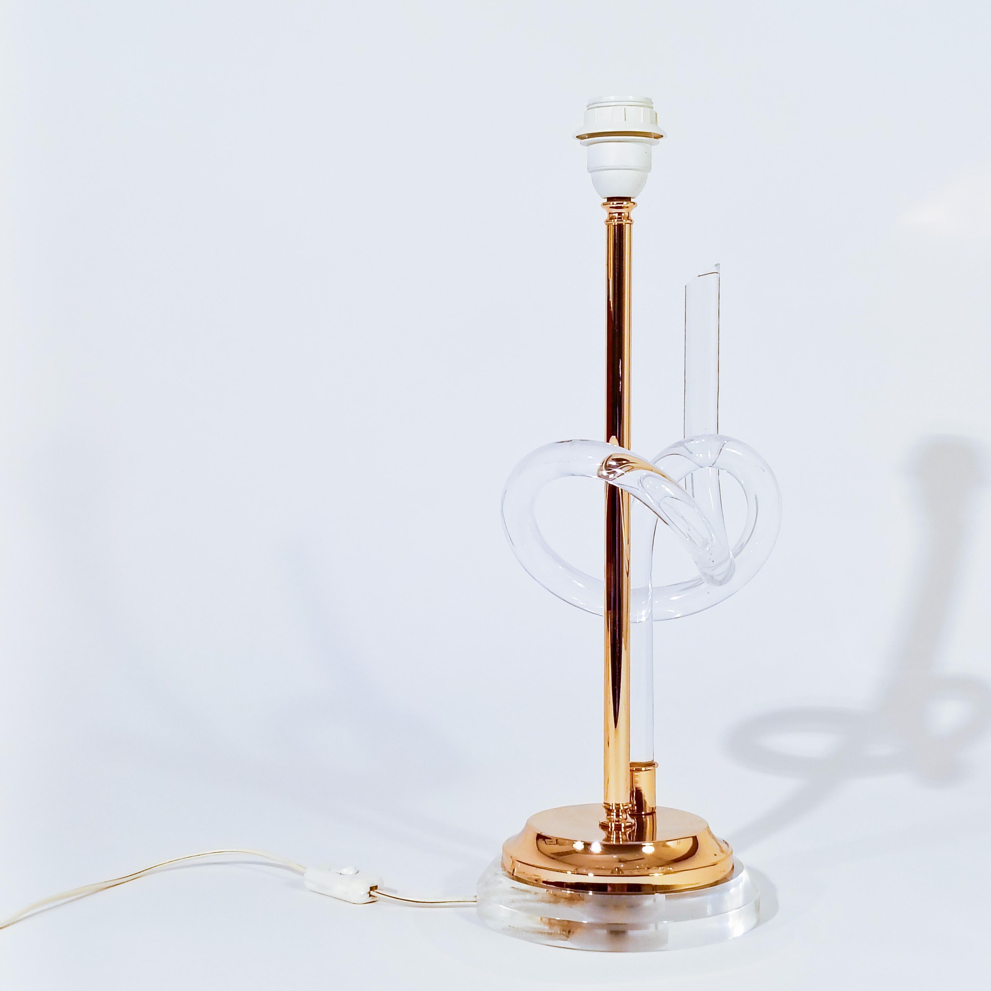 Table lamp designed by Elaine Bscheider for Dorothy Thorpe Inc., USA, 1970s. Composed of a transparent methacrylate base on which a golden chrome metal structure stands with an acrylic prezel as a sculpture. This prezel shape is the typical element