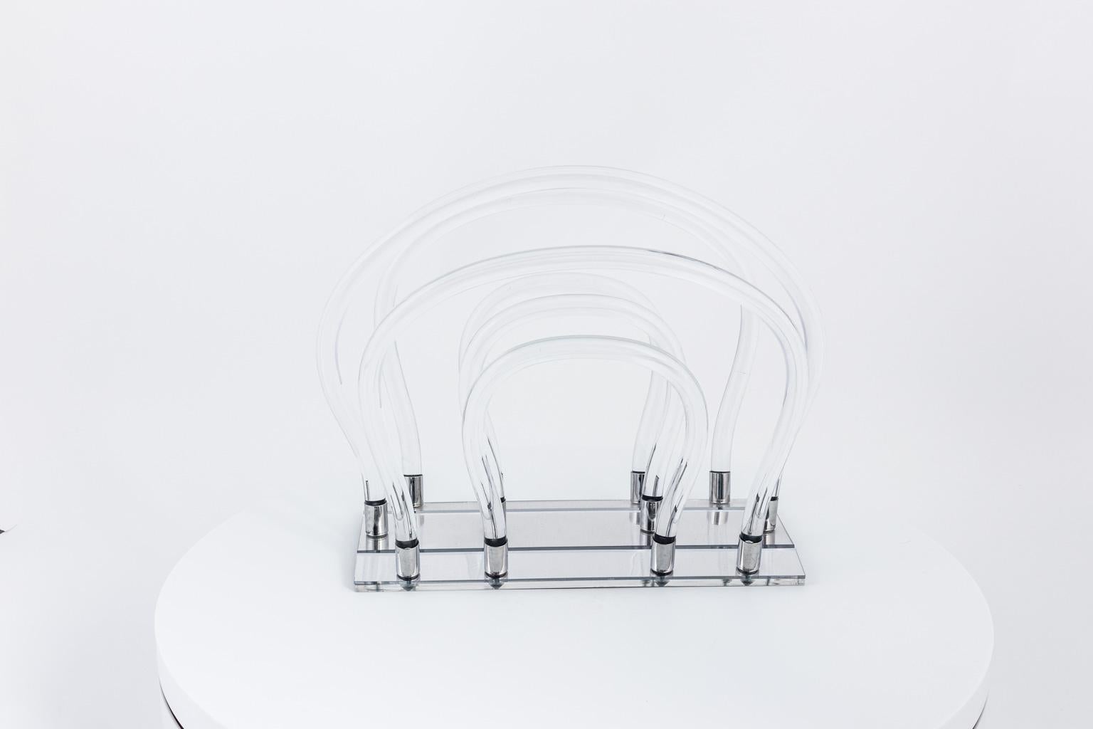 Dorthey Draper Lucite magazine rack in curved Lucite with mirrored base, circa 20th century.
  