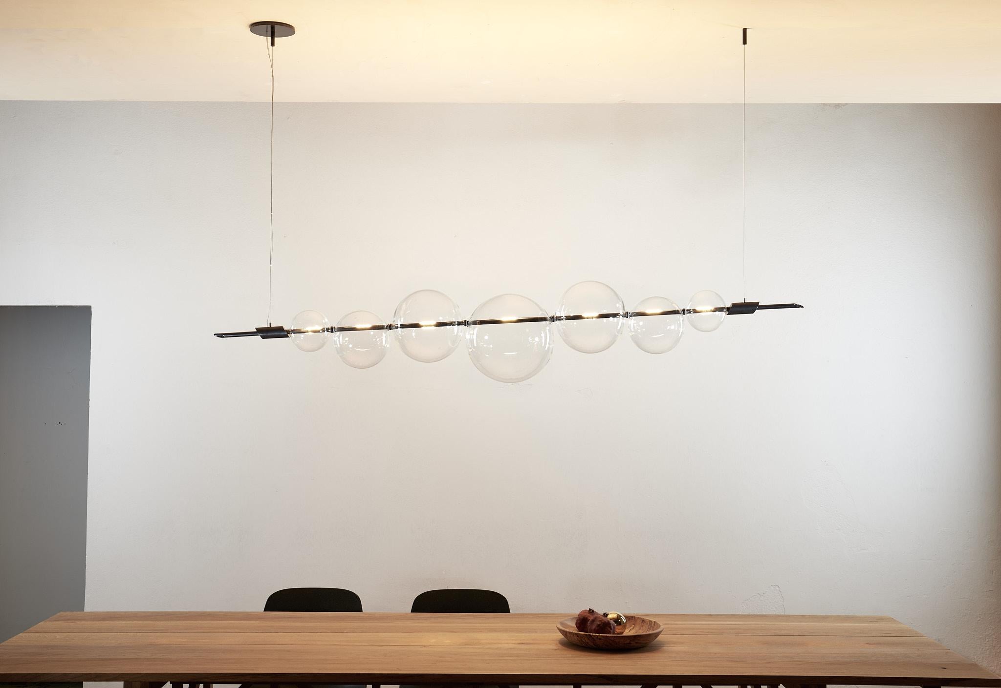 Un exquisito ejercicio de equilibrio,
Esta lámpara de araña emana un estilo minimalista caracterizado por líneas limpias y esenciales. Su sencillo diseño presenta una barra de latón suspendida de un rosetón de latón, que sostiene con elegancia una