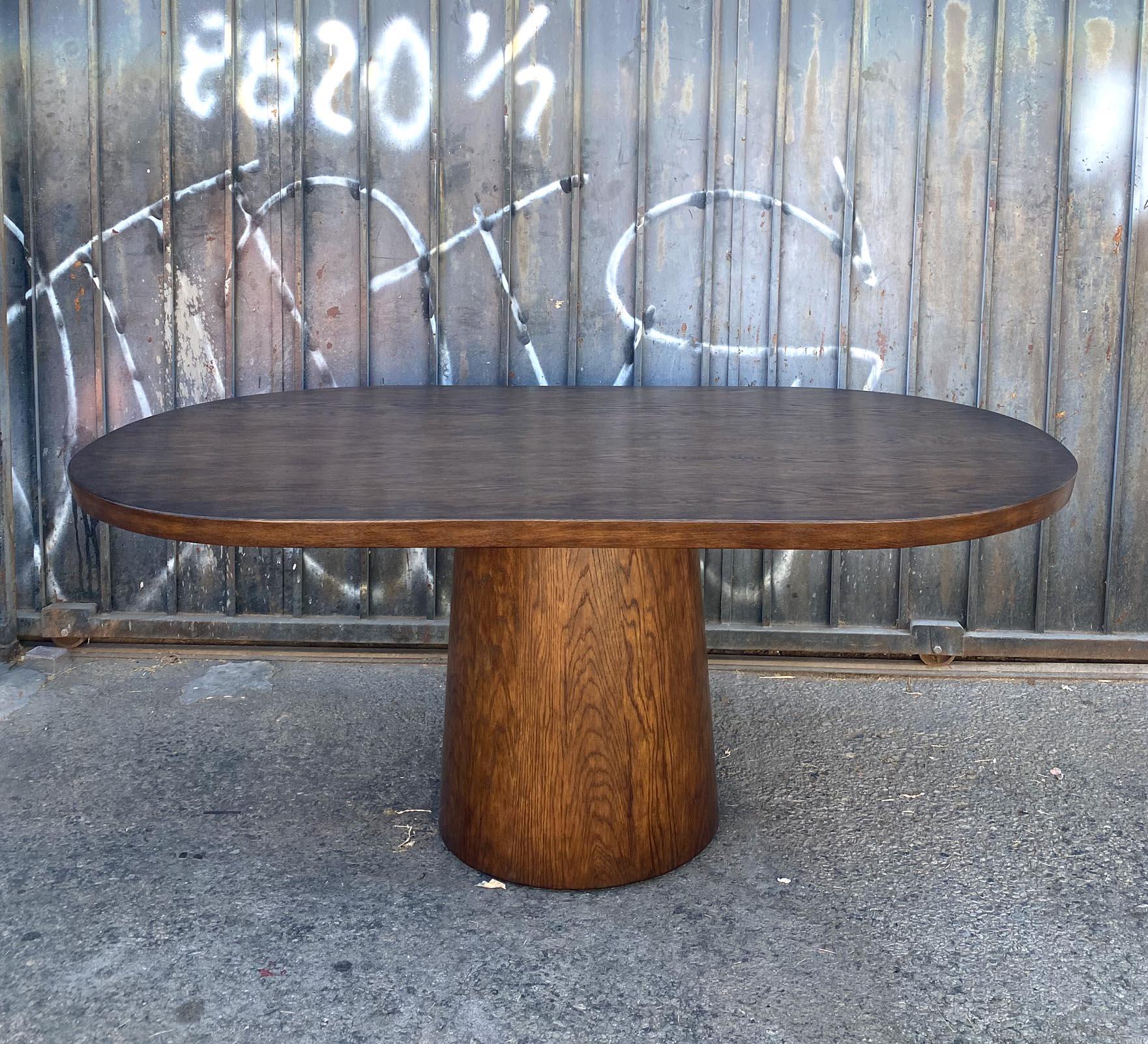 This is a custom cathedral oak table with a tapered, cone shaped round base. The edge is slanted. Solid wood construction. Bench made in Los Angeles by Dos Gallos Studio and hand finished in a walnut #2. The top is hand planed to add interest and