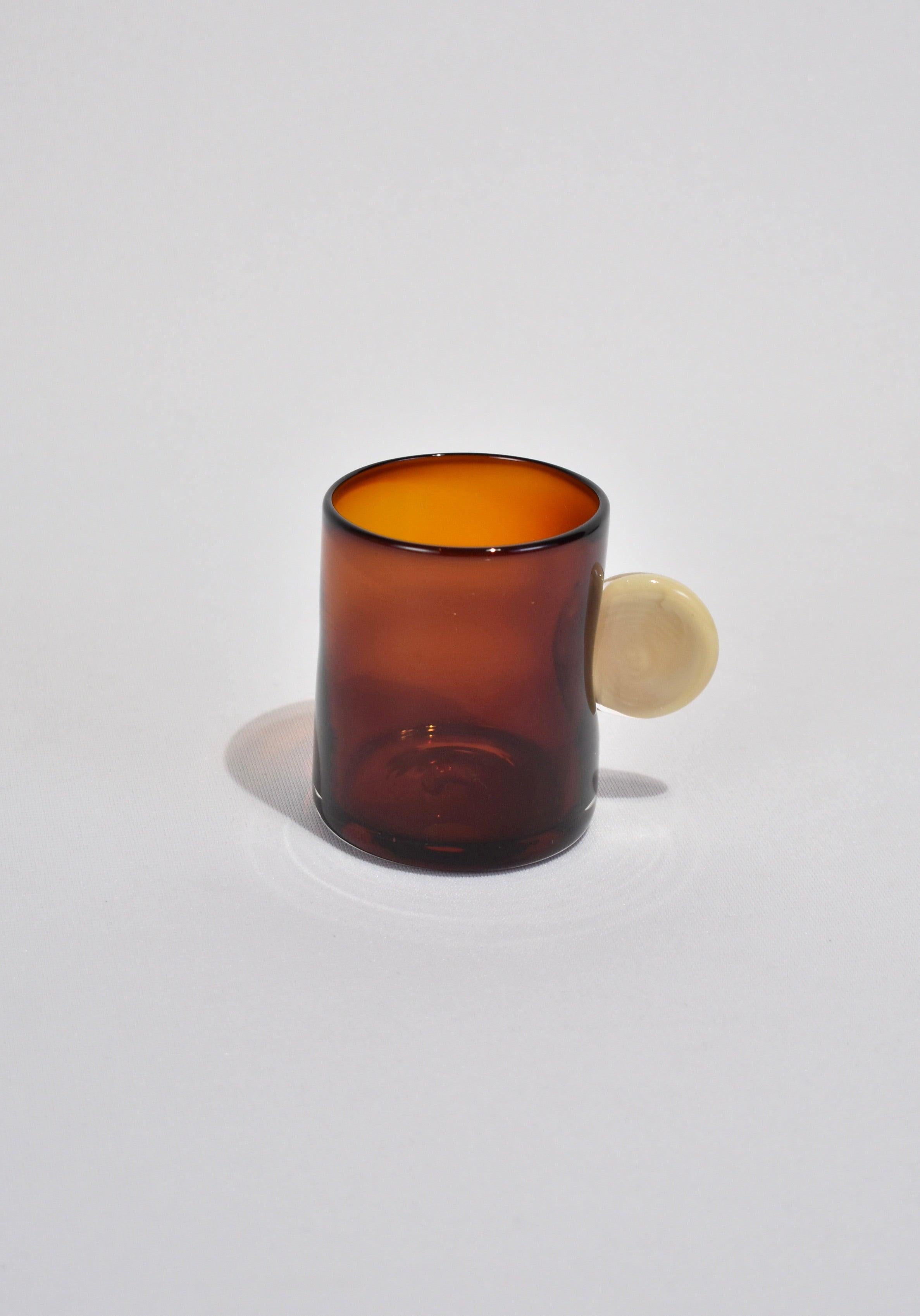 Blown glass tumbler in amber with a cream handle. Perfect size for water, wine, juice, or spirits. Handmade in USA by Grace Whiteside of Sticky Glass.

Please note: Due to the handmade nature of this cup, subtle variations in form and finish are