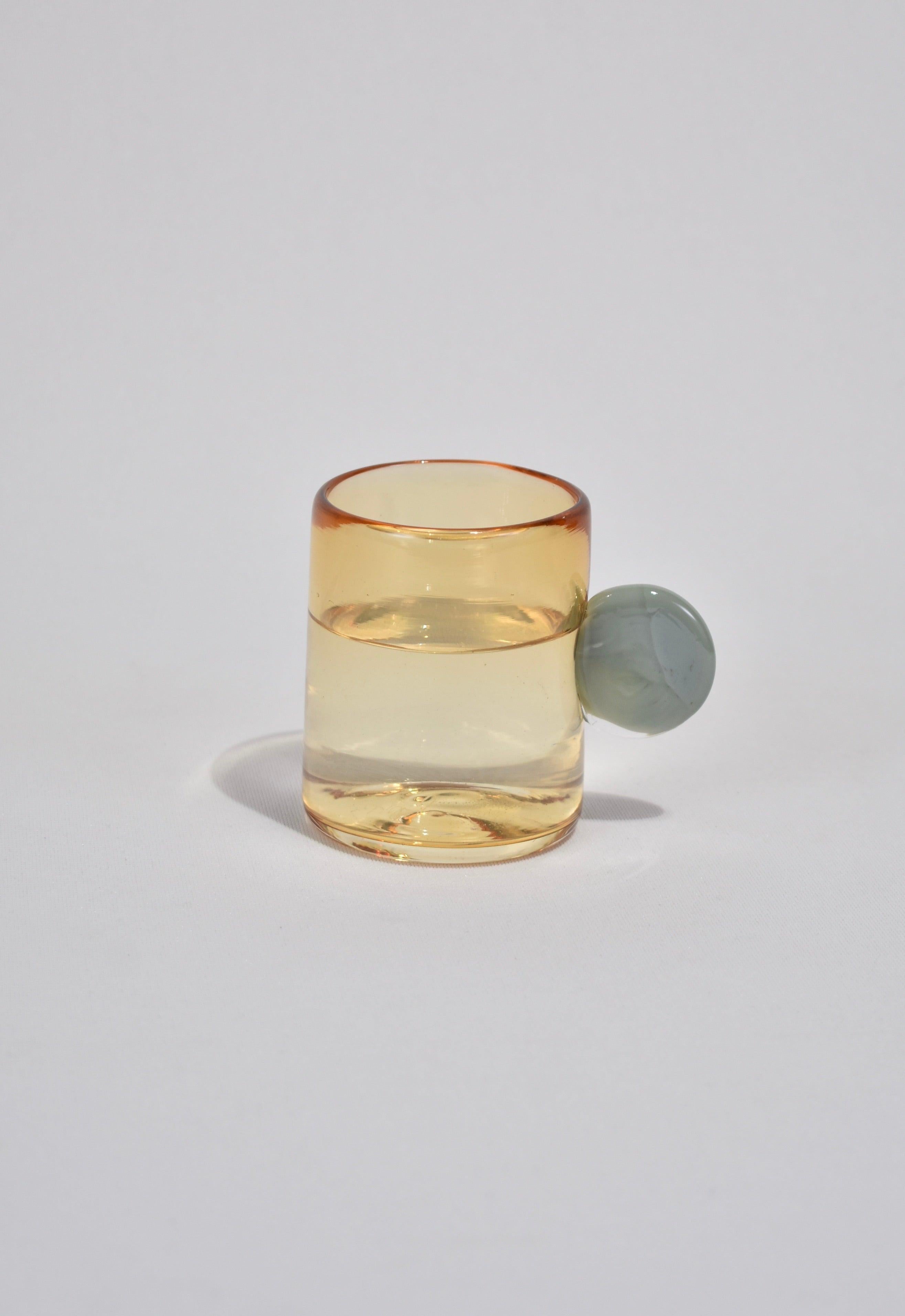 Blown glass tumbler in whiskey with a grey handle. Perfect size for water, wine, juice, or spirits. Handmade in USA by Grace Whiteside of sticky glass.

Please note: Due to the handmade nature of this cup, subtle variations in form and finish are