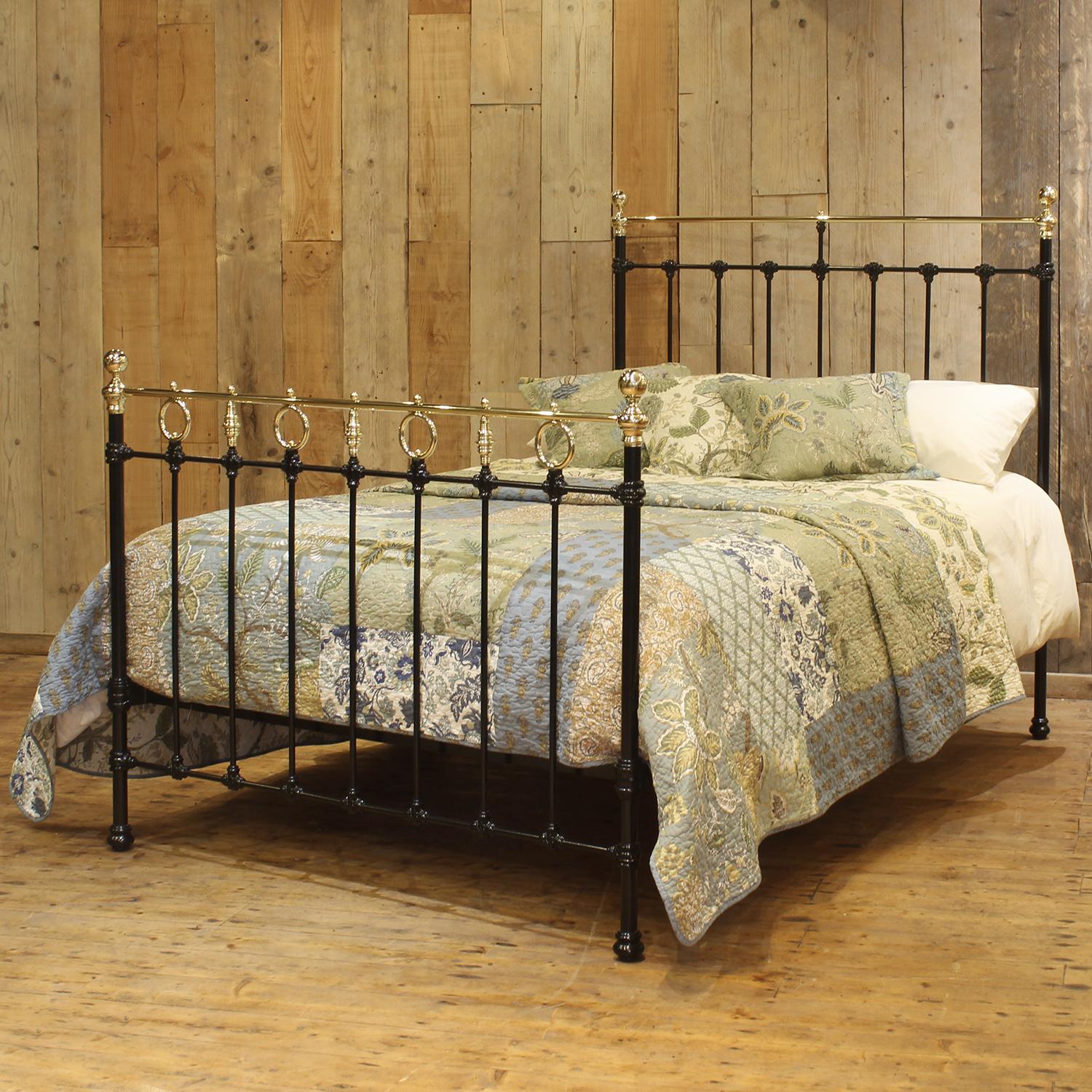 A late Victorian brass and iron bedstead finished in black with straight brass top rails, spherical brass knobs and a gallery of rings and trumpets in the footboard.

This bed accepts a double size 4ft 6in wide (54 inch or 135cm) base and