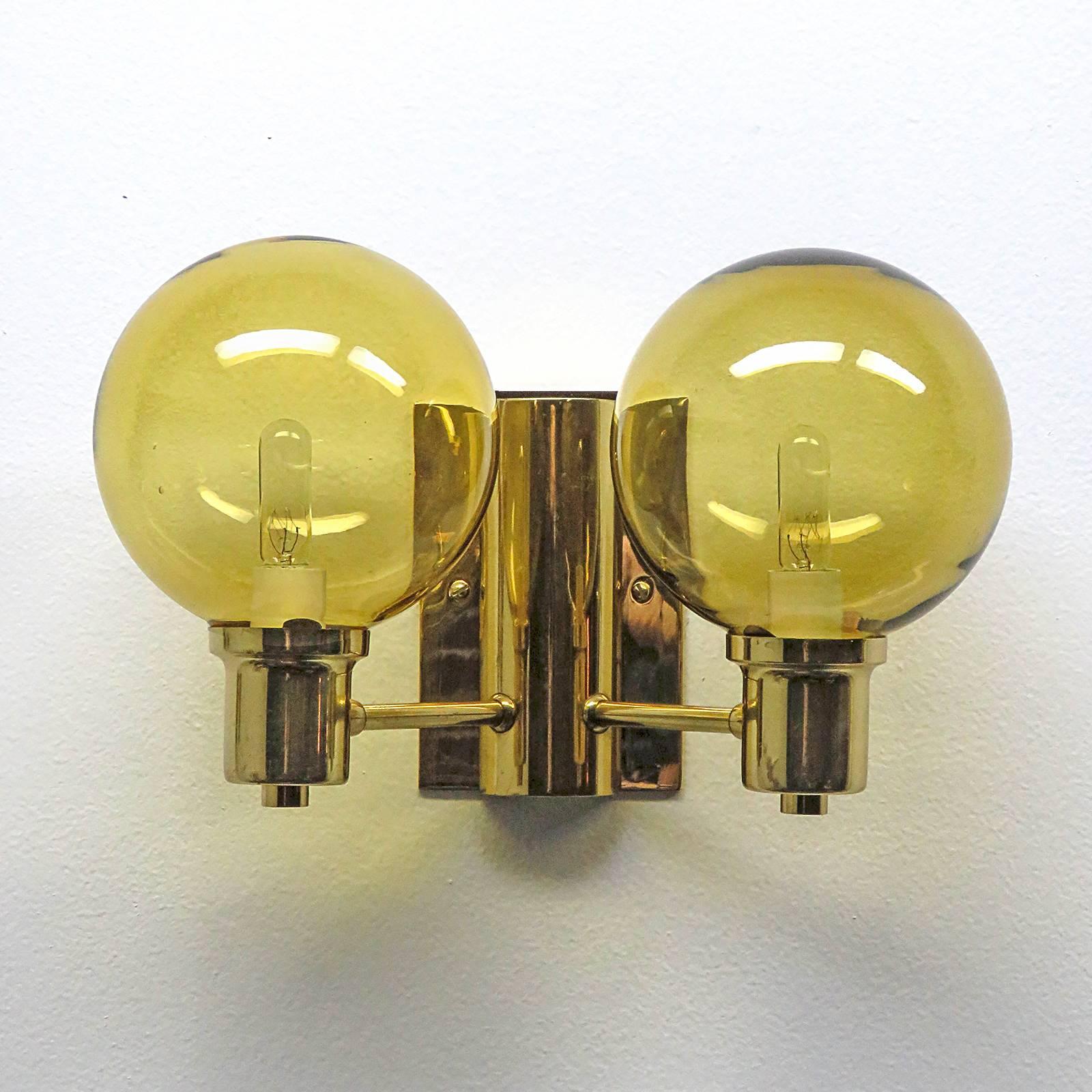 Wonderful Swedish double arm wall lights by Hans Agne Jakobsen with amber colored cut glass shades, custom backplate for US j-boxes, rewired for US, two E12 sockets per fixture, max. wattage 40w per socket, bulbs provided as a one time courtesy.