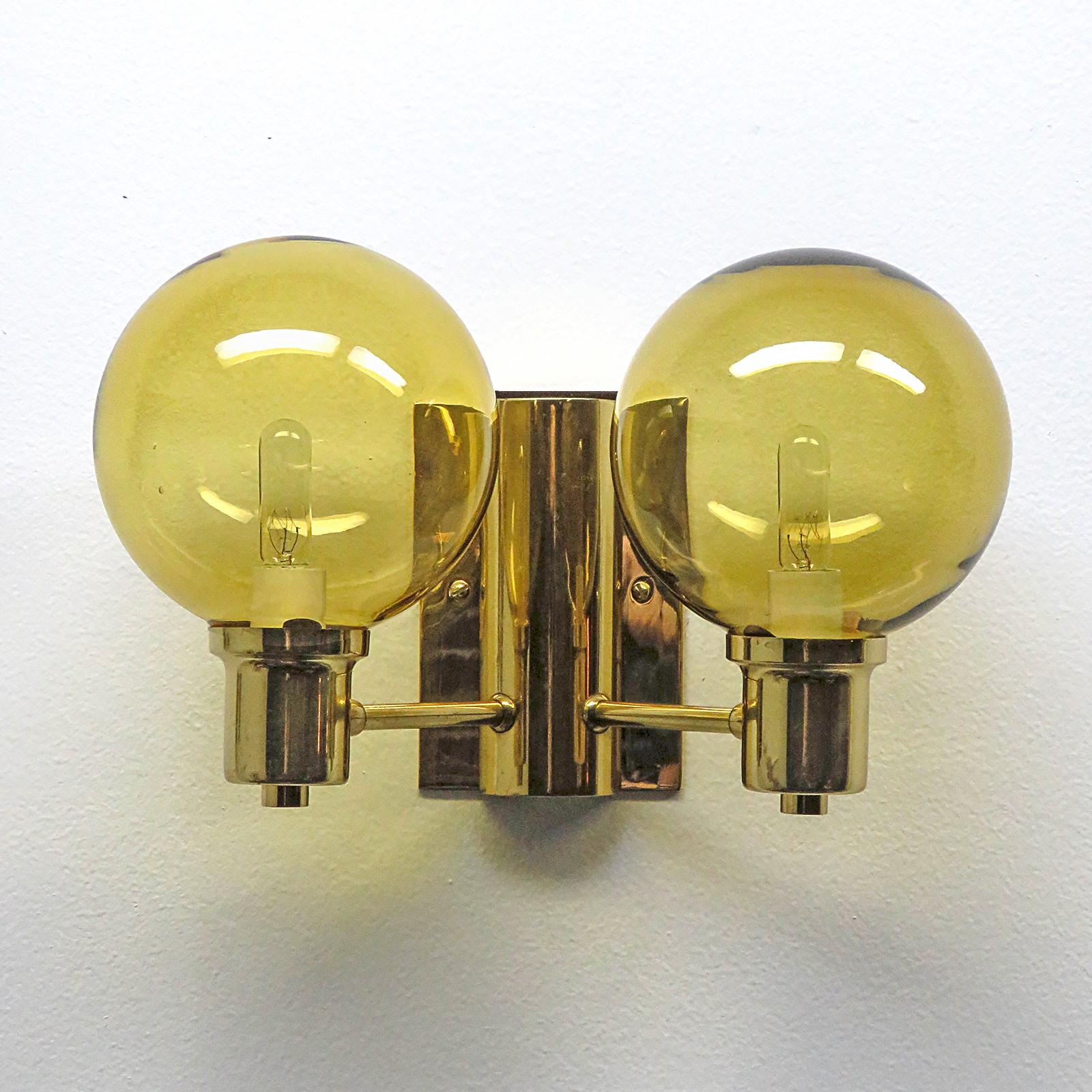 Wonderful Swedish double arm wall lights by Hans Agne Jakobsen with amber colored cut glass shades, custom backplate for US j-boxes, wired for US standards, two E12 sockets per fixture, max. wattage 40w per socket, bulbs provided as a one time