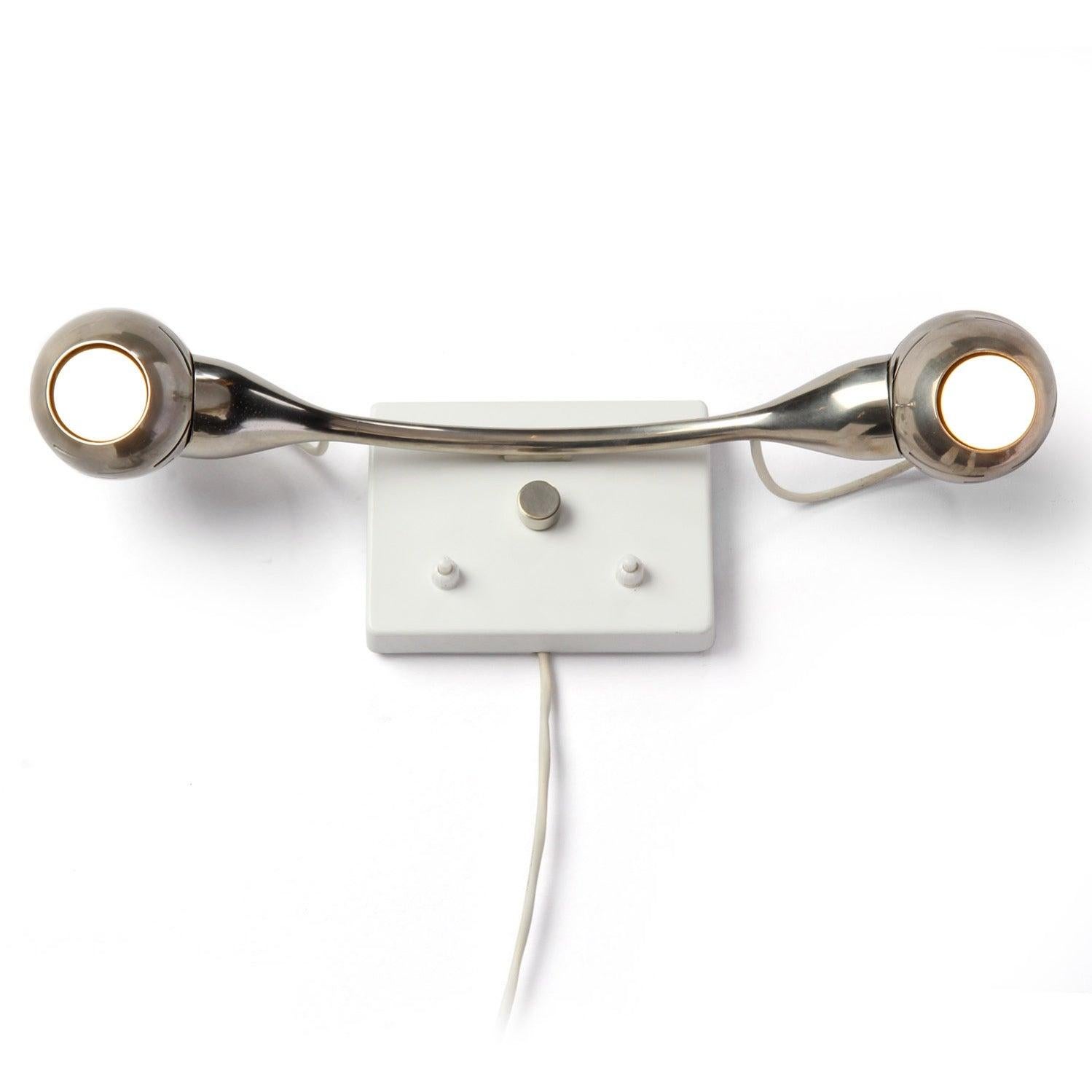 Aplique o candelabro de pared modernista que tiene dos luces de bola y casquillo magnéticos cromados ajustables fijados a un brazo de acero cromado que sobresale de una placa de montaje de pared esmaltada.
