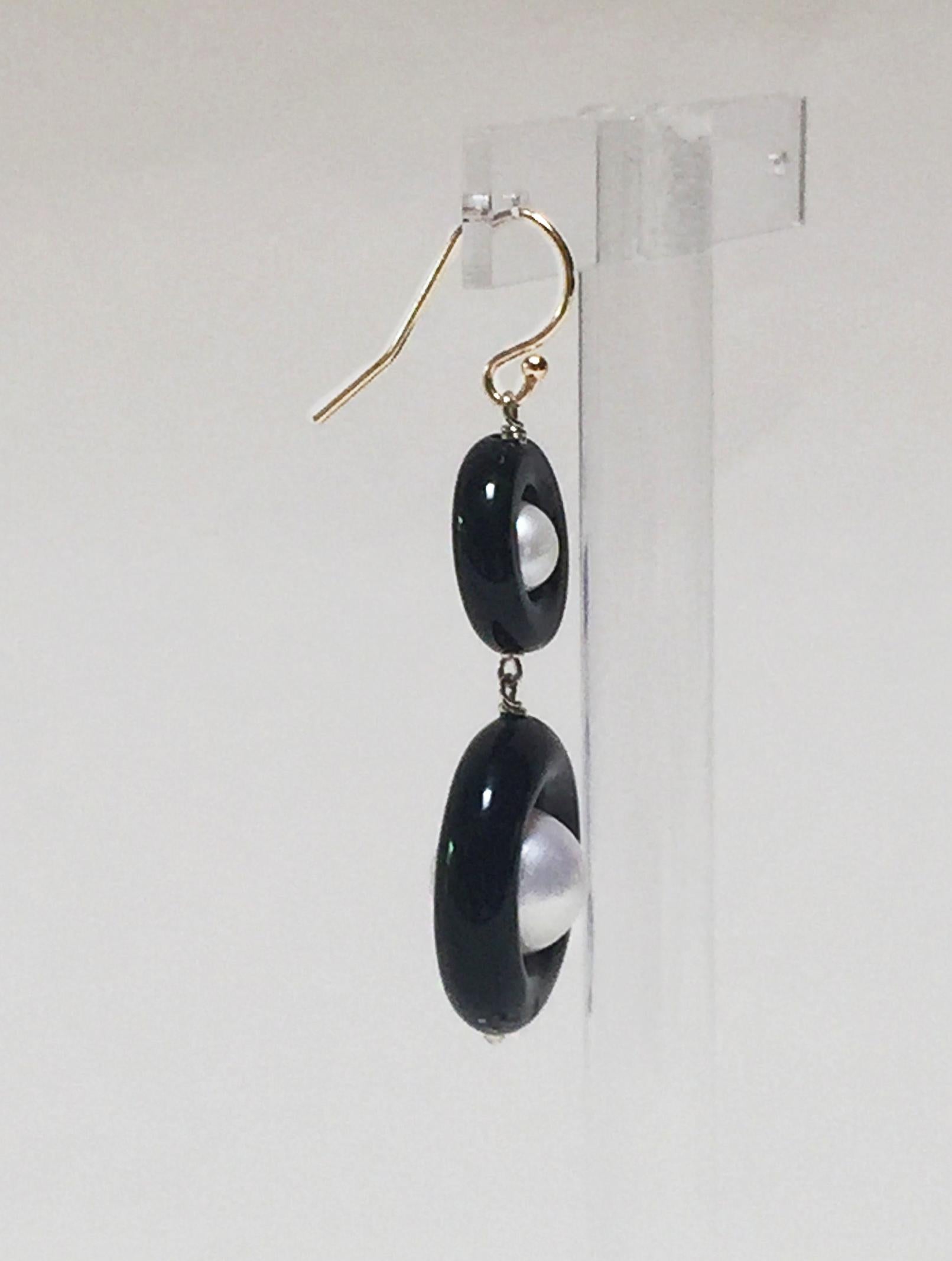 These classic double black onyx and pearl earrings with 14 k yellow gold hook and wiring are elegant and bold. The onyx rings contrast with the glowing white pearls beautifully making, what could have been simple earrings dramatic and eye-catching.