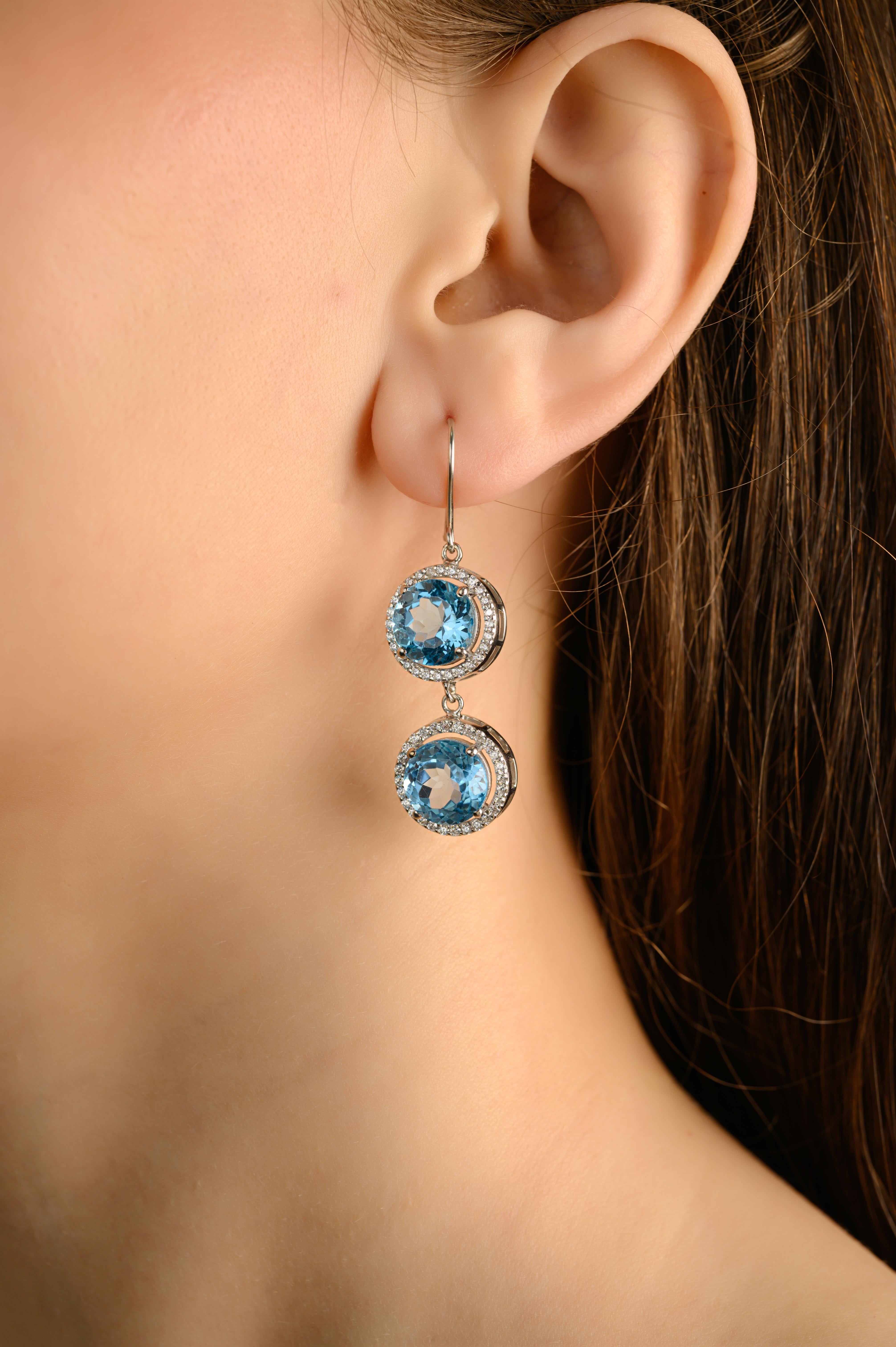 Diese doppelten Halo-Blautopas-Tropfenohrringe aus Silber mit Zirkon zeichnen sich durch zwei lebhafte Blautopase im Rundschliff aus, die jeweils von einem Halo aus funkelnden weißen Steinen umgeben sind. Sie sind in leuchtendem 925er Sterlingsilber