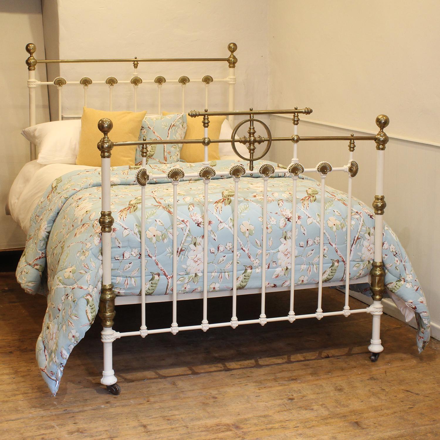 A cast iron and brass antique bed, finished in white with brass rosette decoration and brass gallery on the foot end with central feature of a brass ring. 

This bed accepts a double size 4ft 6in wide (54 inch or 135cm) base and
