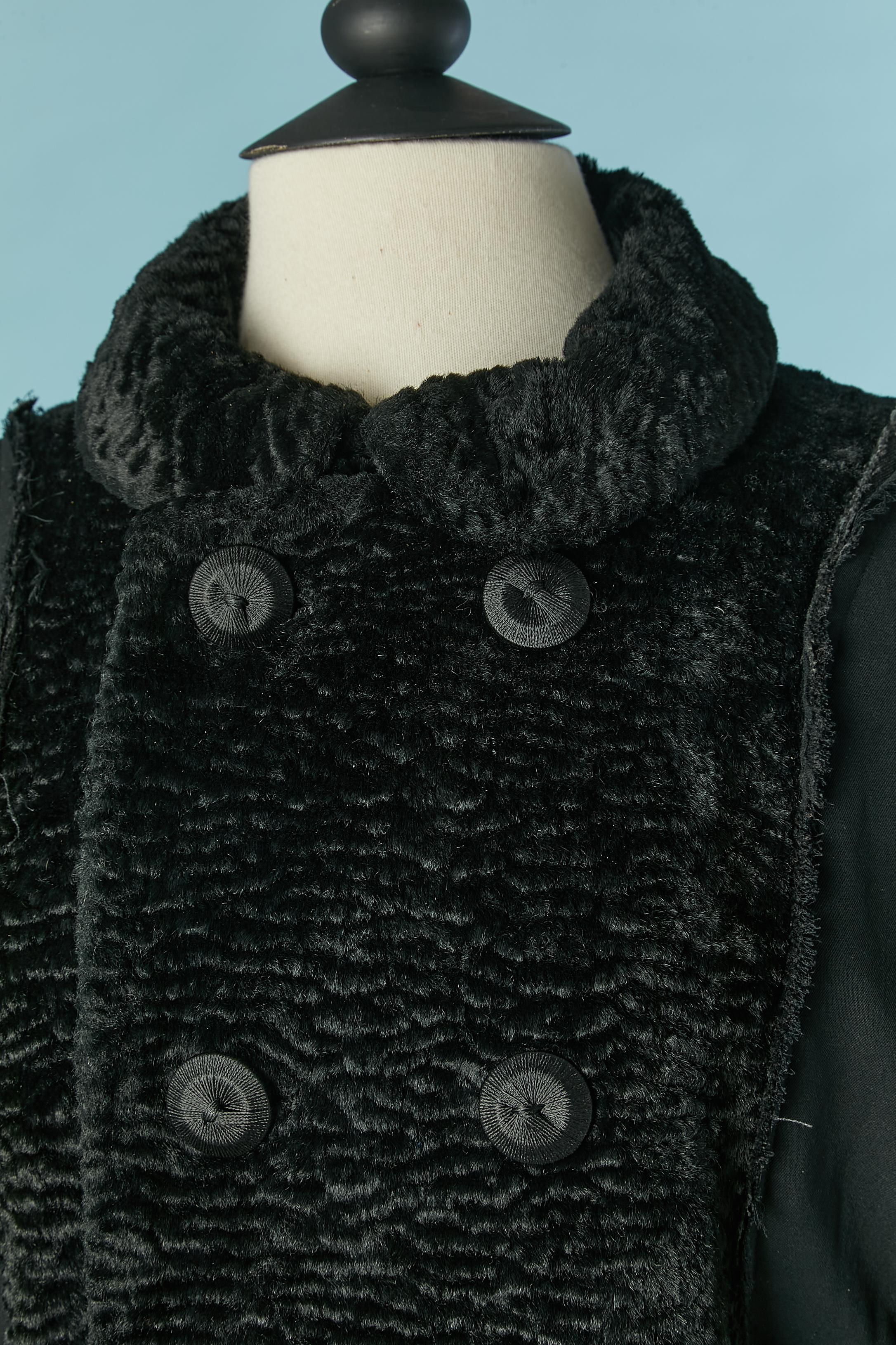 Cappotto doppiopetto nero con pelliccia sintetica. Non è possibile leggere la composizione del tessuto, ma il tessuto nero è probabilmente rayon e anche la fodera. 
Spallaccio. Bottone a filo e chiusura ad asola sul  fronte . Bottone e asola sui