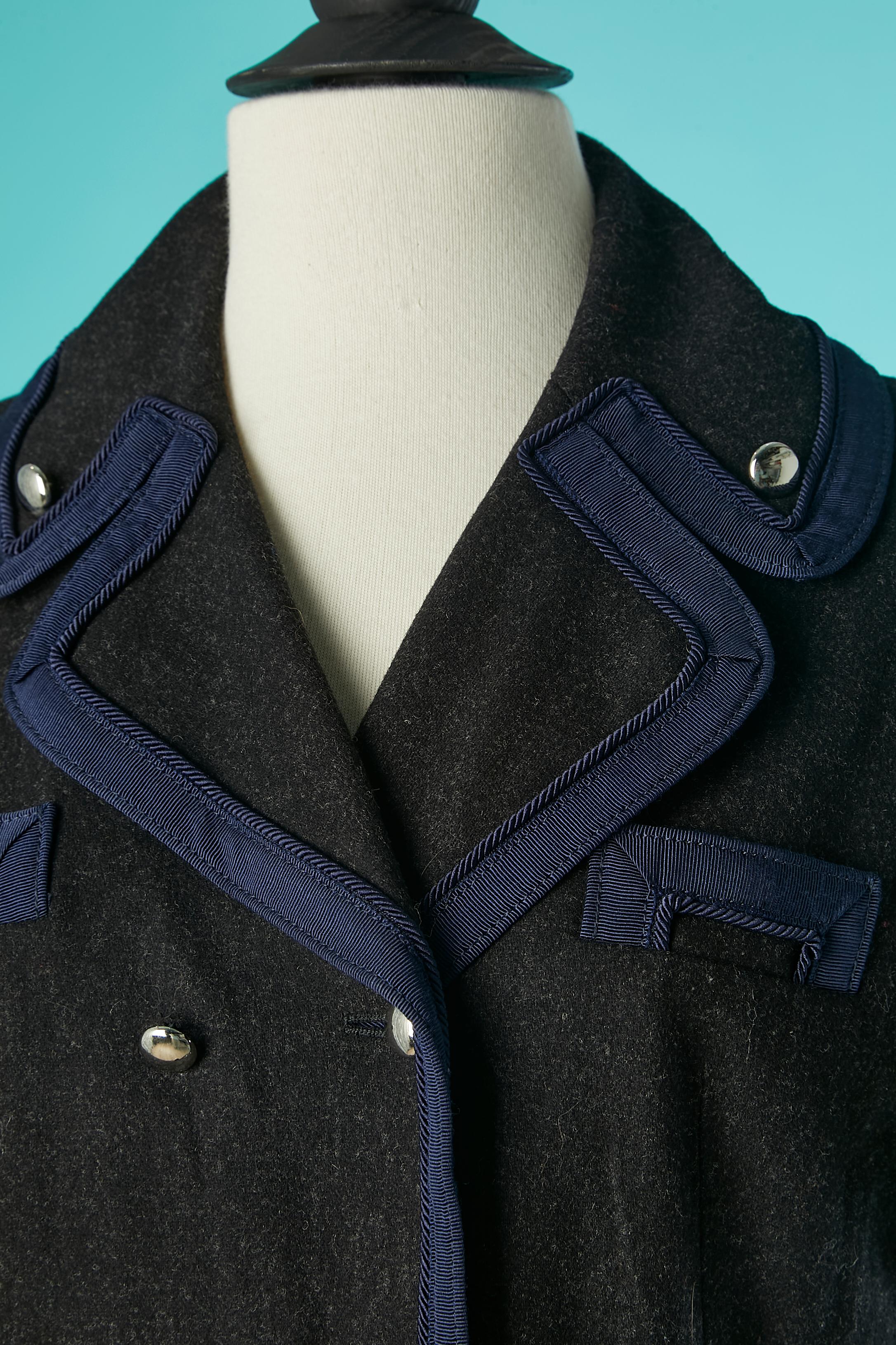 Double breasted grey wool jacket with blue piping. Main fabric composition: 78% wool, 20% nylon, 2% lycra. Lining: 95% polyester, 5% spandex. 
Gros-grain and passementerie probably in rayon. 
SIZE 8 