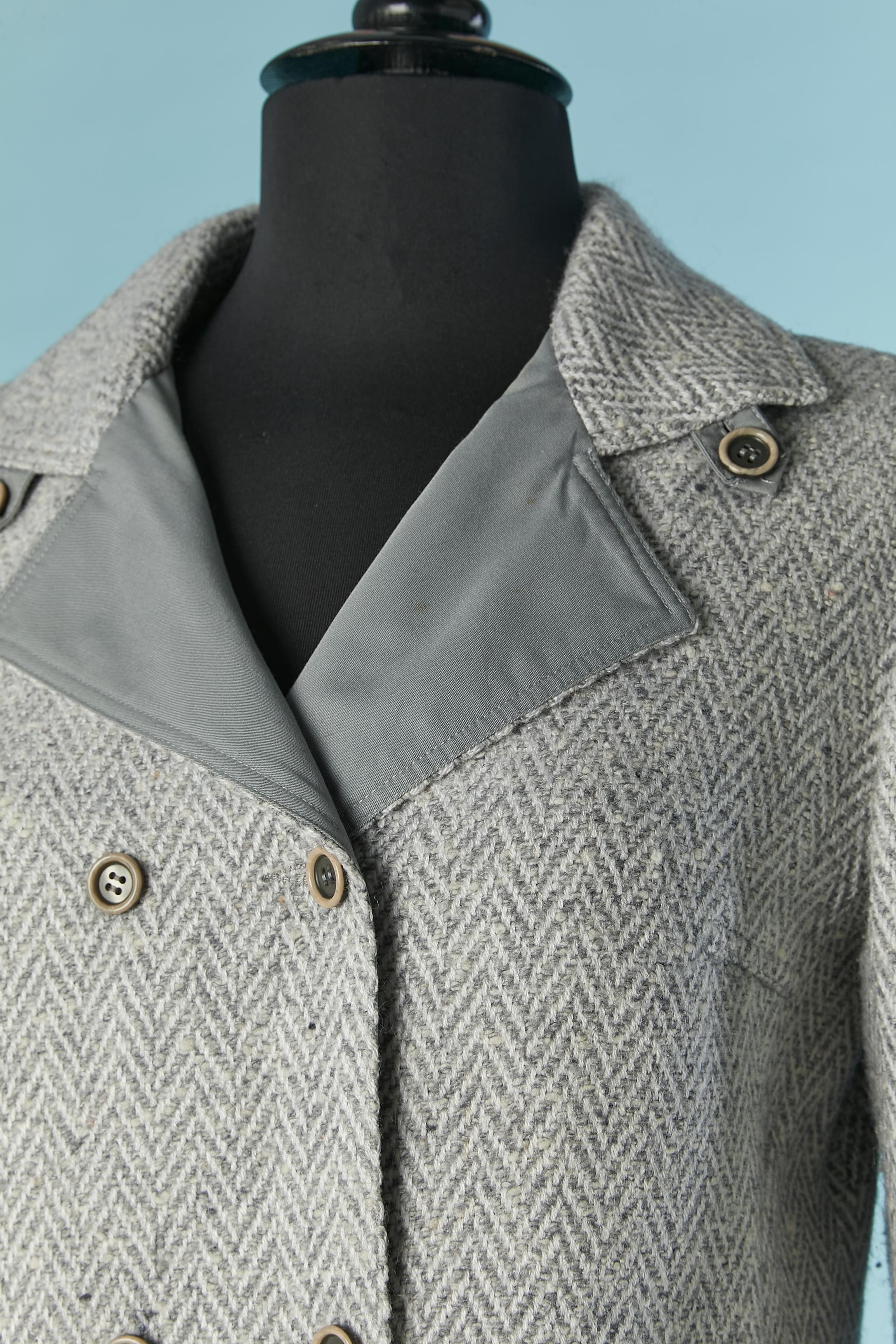Double breasted skirt suit in tweed with chevron pattern. Main fabric composition: 45% acrylic, 42% wool, 13% rayon. Inset composition ( grey fabric : on collar, pockets and elbow) : 67% polyester, 33% cotton. Lining: 100% acetate. 
SIZE  of the