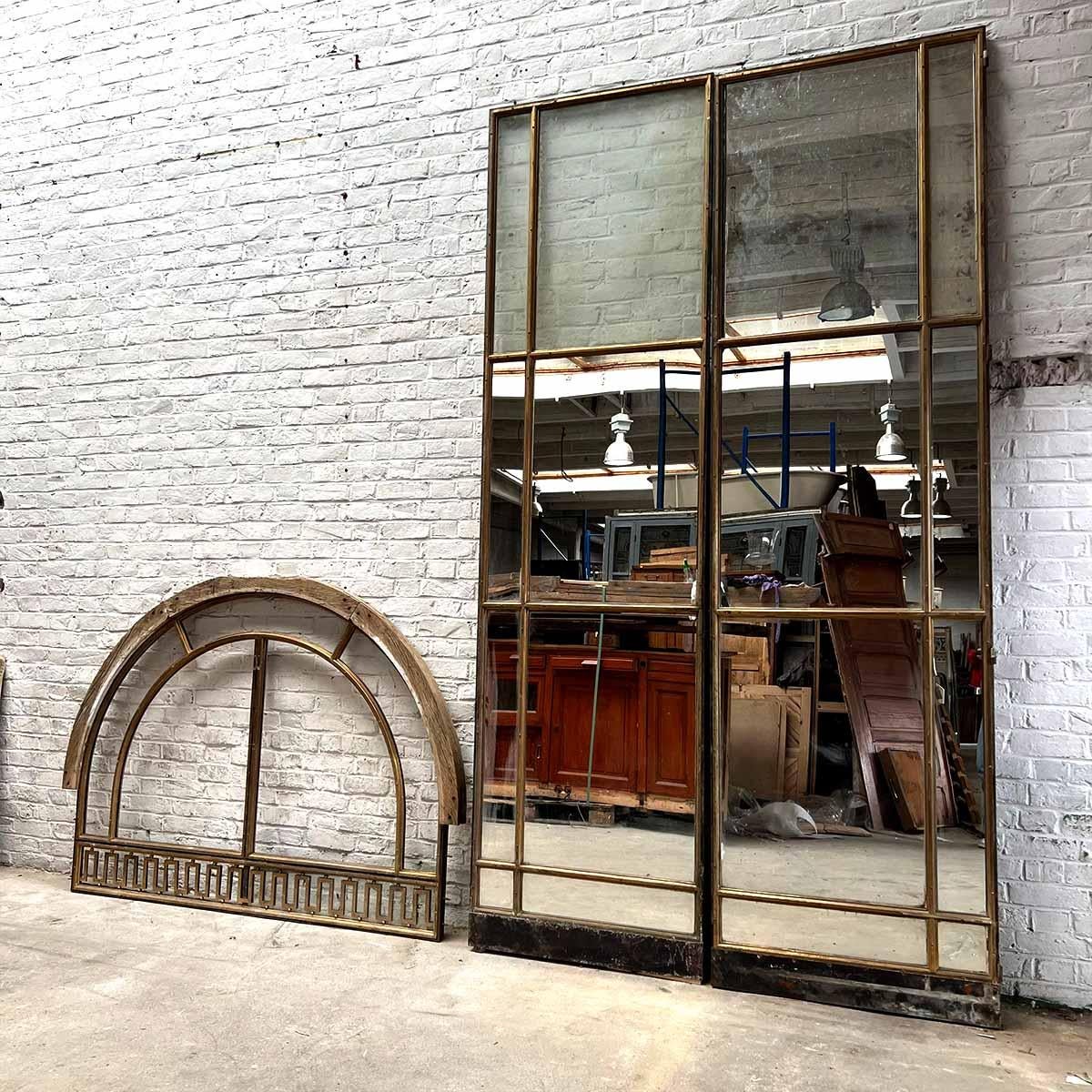 Porta in bronzo a doppio vetro con sopraluce
Dimensioni: 168 × 428 cm

Questa eccezionale porta a due battenti in bronzo presenta pannelli originali in vetro antico e un elegante traverso con cornici architettoniche curve. Raro pezzo di recupero