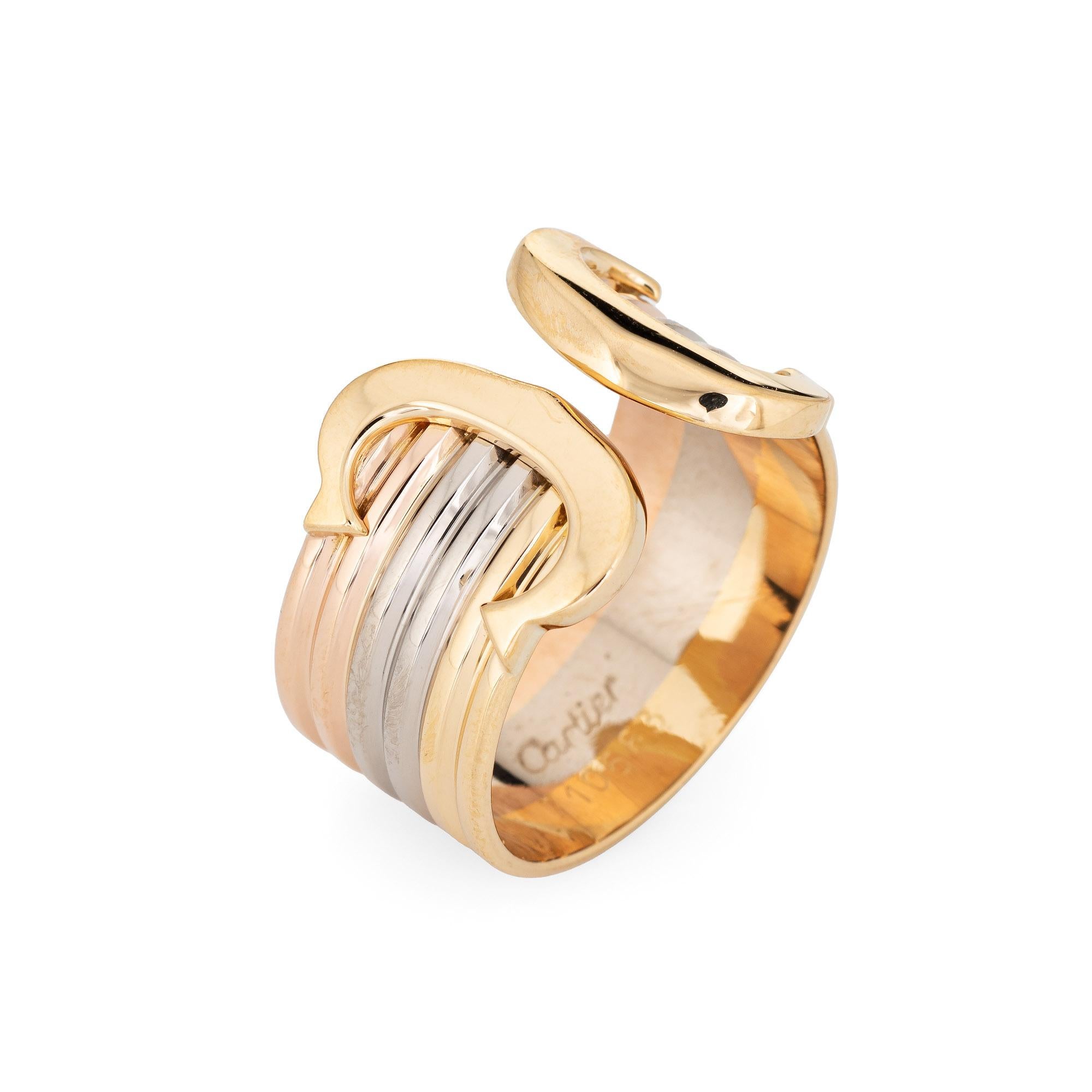 Out of production vintage Double C de Cartier ring crafted in 18k yellow, rose and white gold (circa 1990s).  

The iconic Cartier ring features bands of 18k yellow, rose and white gold. The wide band measures 10mm (0.39 inches). The ring is great