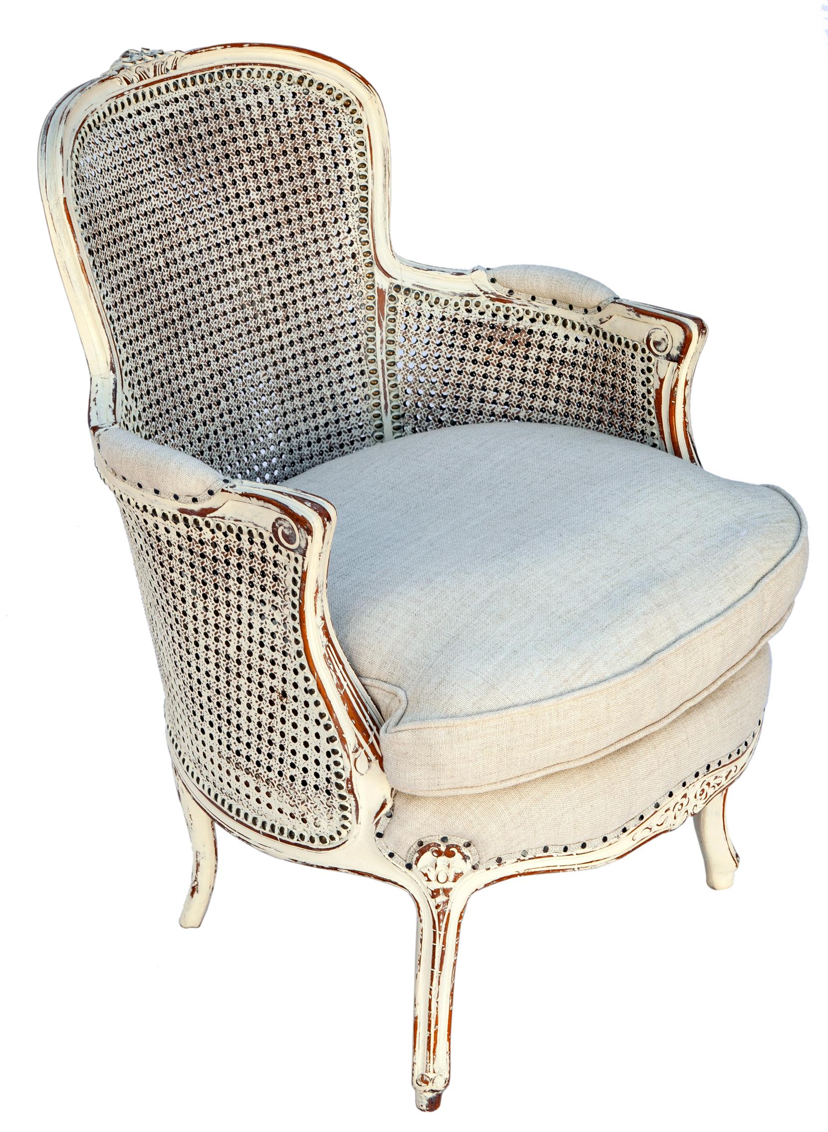 Antique French carved armchair with double caned back and side panels. 
Floral rosettes at the top, bottom, apron & legs. 
Double-caned, hand-carved with new paint.
New linen upholstery in Italian linen blend down/feather cushion.
Seat to floor