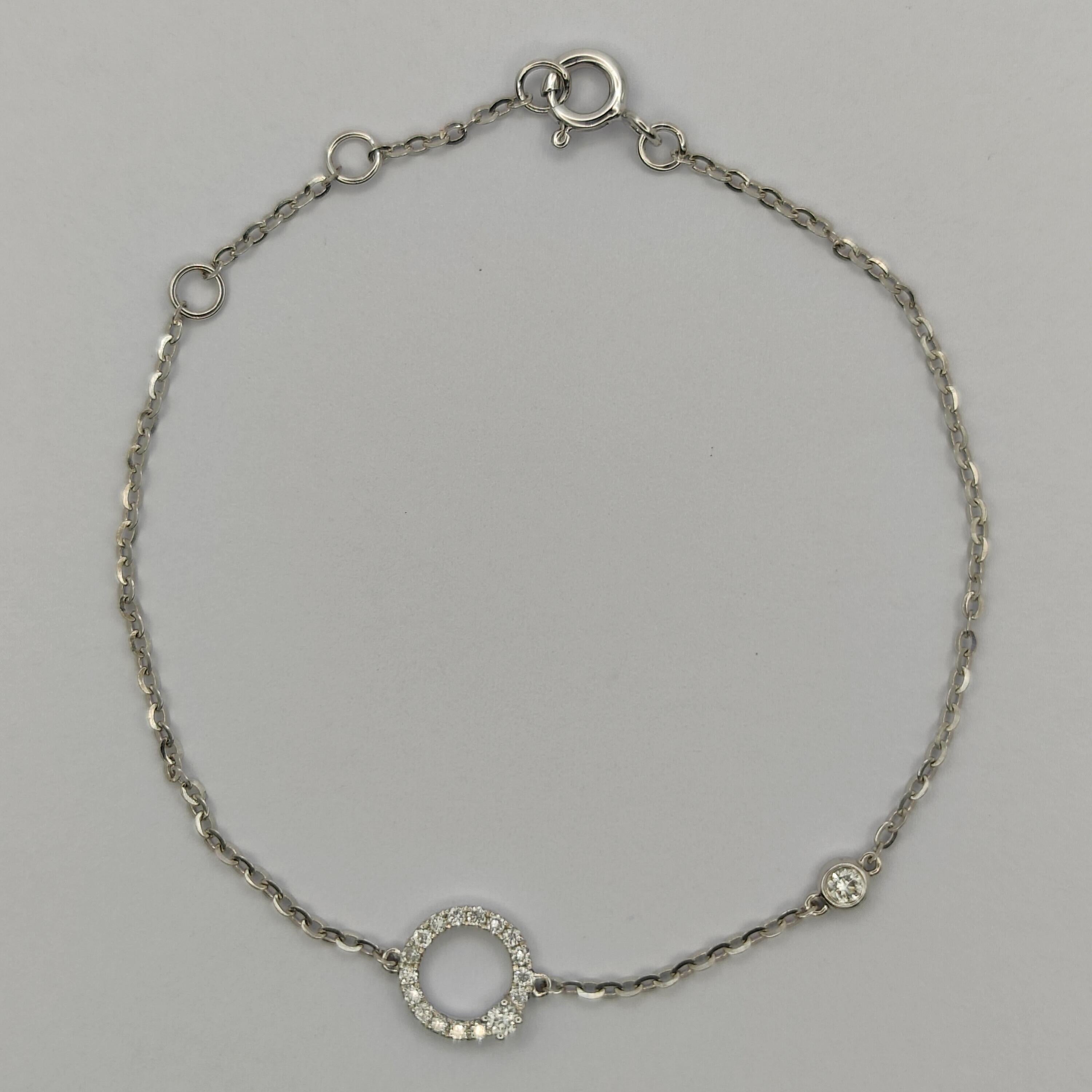 Dieses wunderschöne Diamantarmband besteht aus einem einzigen Kreis funkelnder Diamanten mit einem größeren, freistehenden Diamanten als Herzstück. Das Armband ist aus 18 Karat Weißgold gefertigt, was ihm ein zeitloses und elegantes Aussehen
