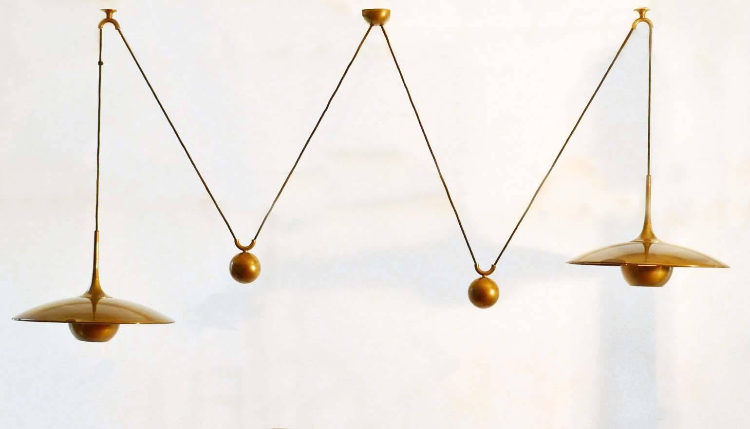 Double counterbalance pendant Onos 40 by Florian Schulz, made in the early 1970s. Each of the elegant pendants, in a high quality brass, individually move smoothly up and down due to the solid brass counterweights. The shades are fitted with brass