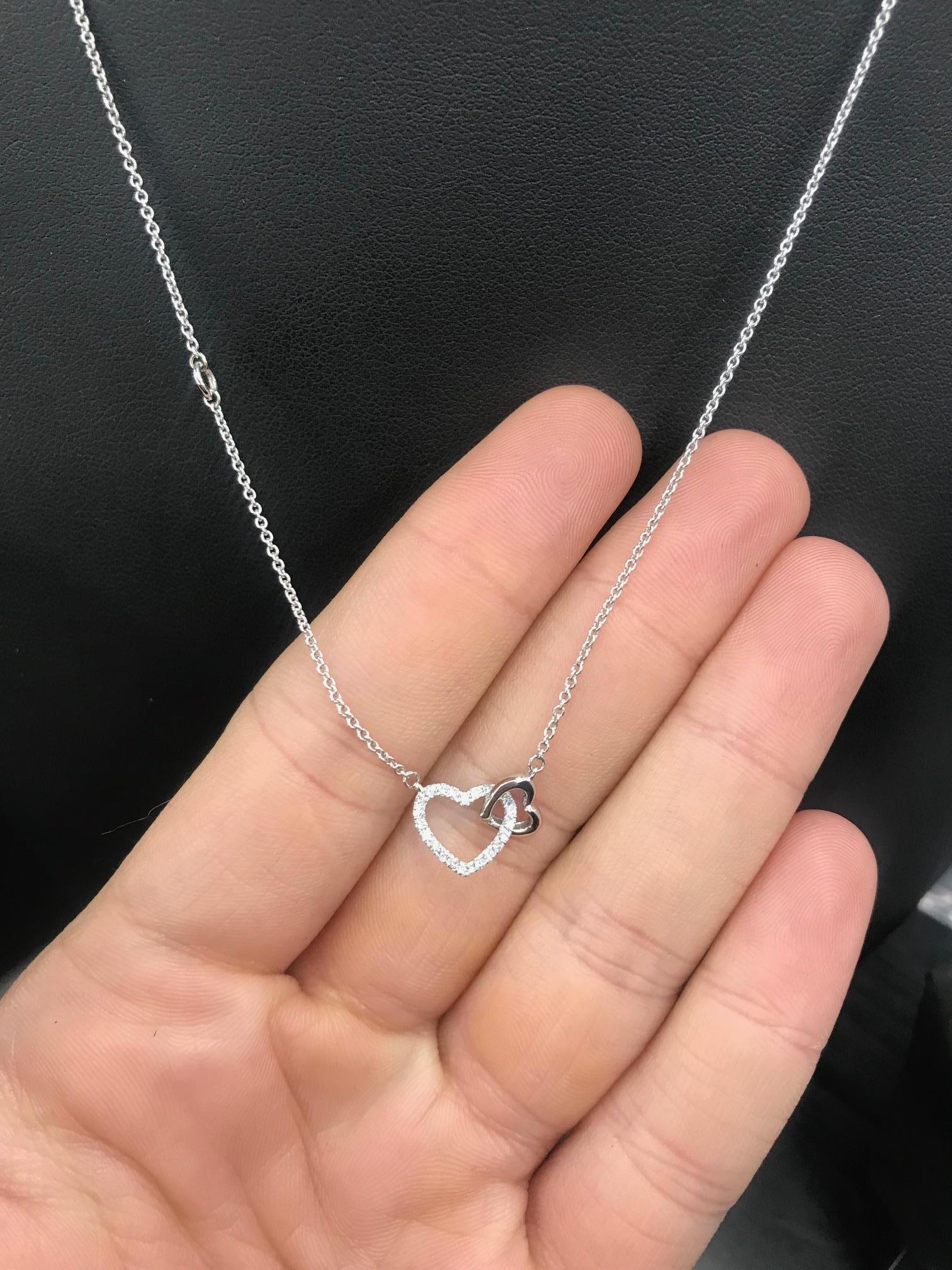 14K White gold double heart necklace featuring round brilliants weighing 0.11 carats.