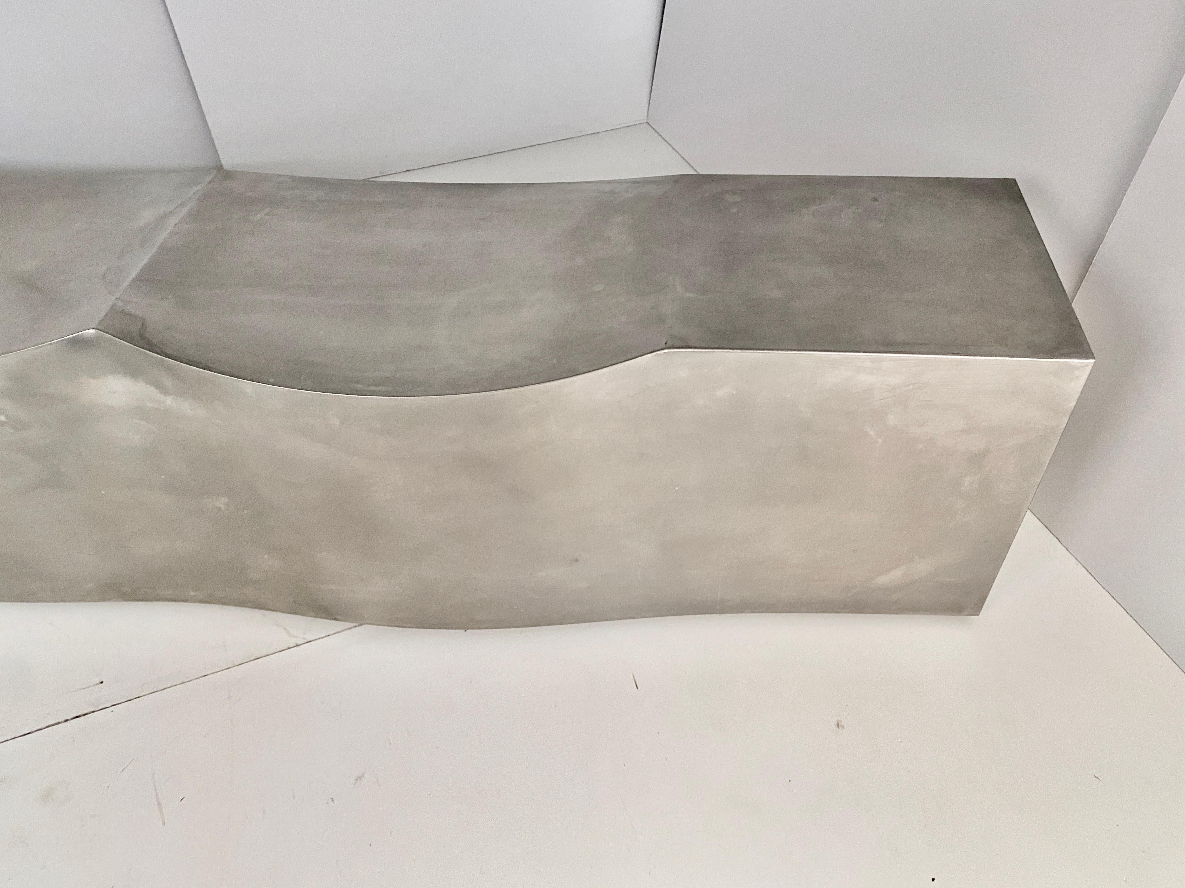 The Double Dip Bench is built using a stainless steel sheet with a thickness of 1.5 mm and a circular sandblasted finish. The distinctive shape is obtained with special technology involving milling, bending and welding. It appears as a sculpted