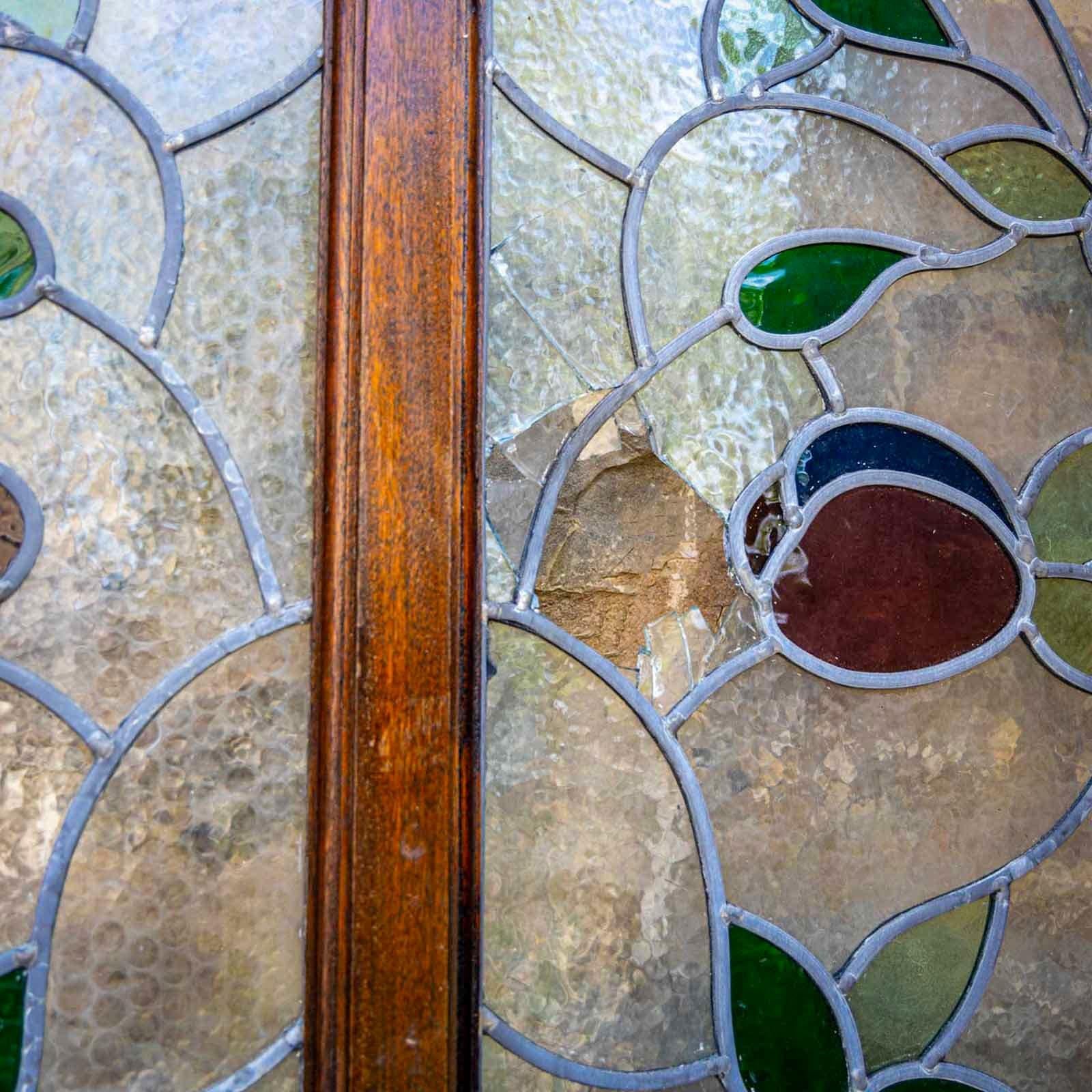 Porte doppie in legno con vetrate tripartite e tre pannelli nella parte inferiore, oltre a vetrate colorate con decorazioni di rose.