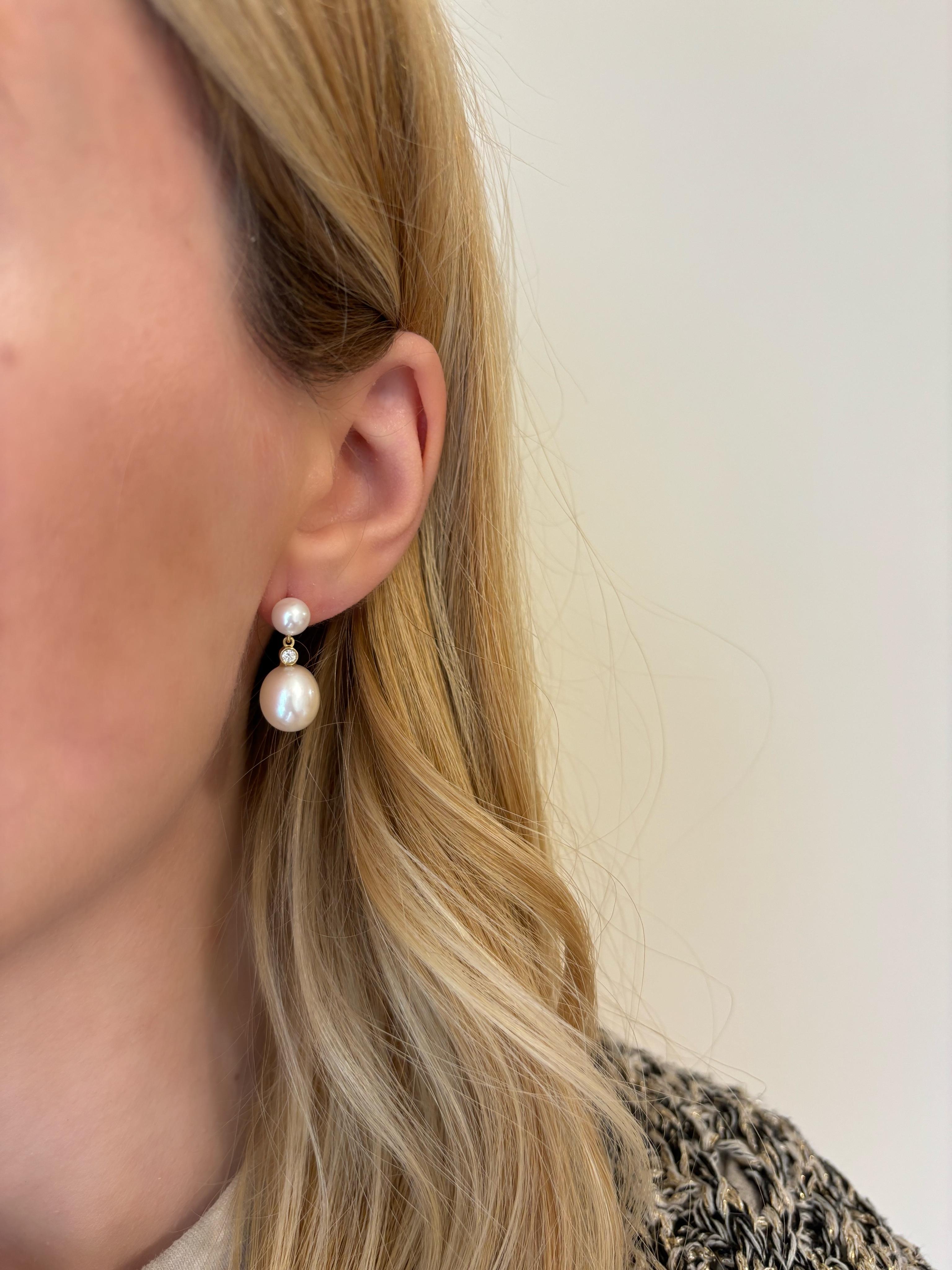 Our double drop pearl earrings, are made in 18Karat Yellow Gold and feature a pair of mini pearls with size 6mm that are strung by a pair of oval shaped freshwater pearls with size 10mm and set with glimmering natural round diamonds with size