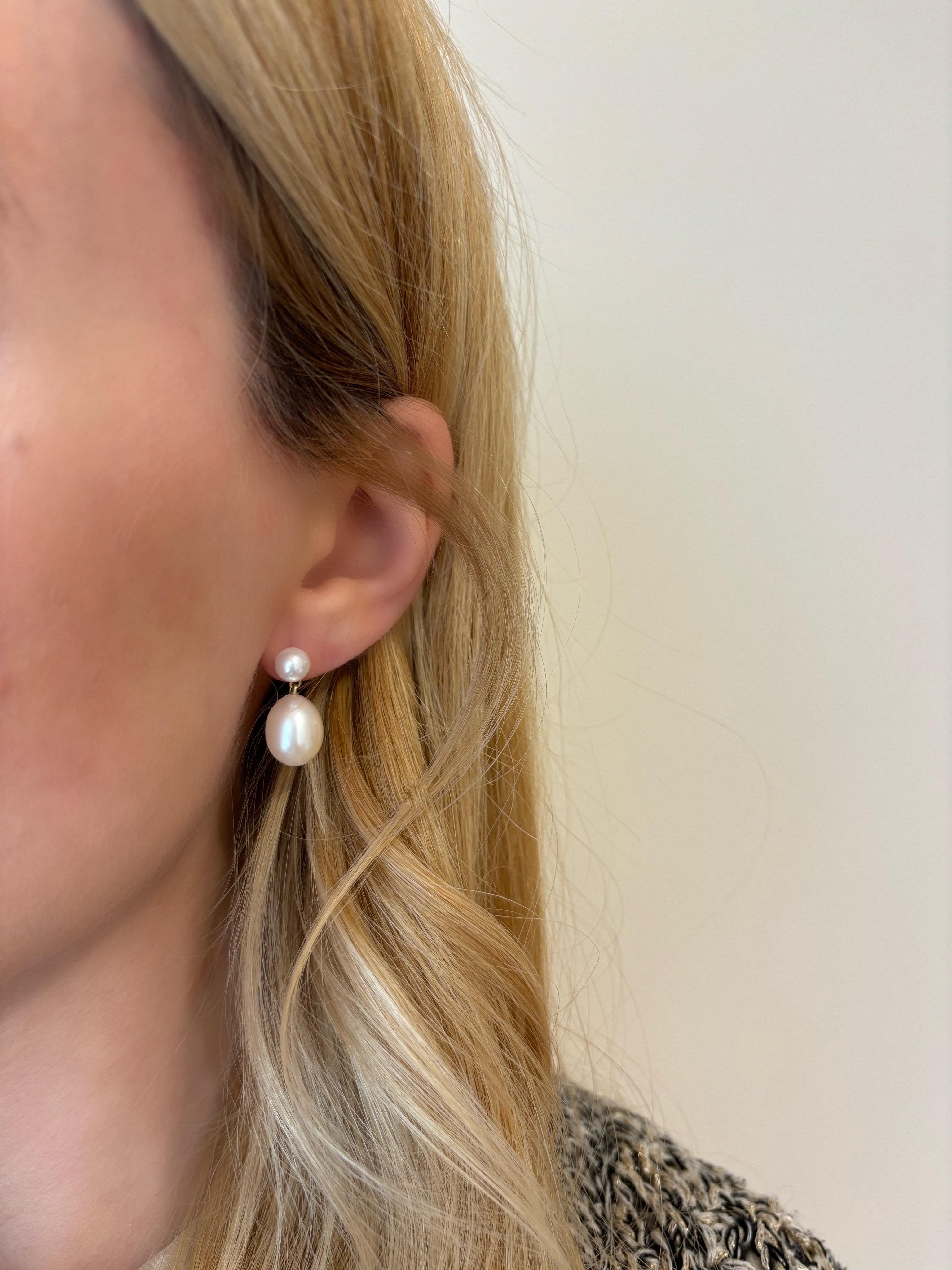 Our double drop pearl earrings, are made in 18Karat Gold and feature a pair of mini pearls with size 6mm that are strung by a pair of oval shaped freshwater pearls, with size 11mm. Due to the organic nature of the pearls every pair is unique and has