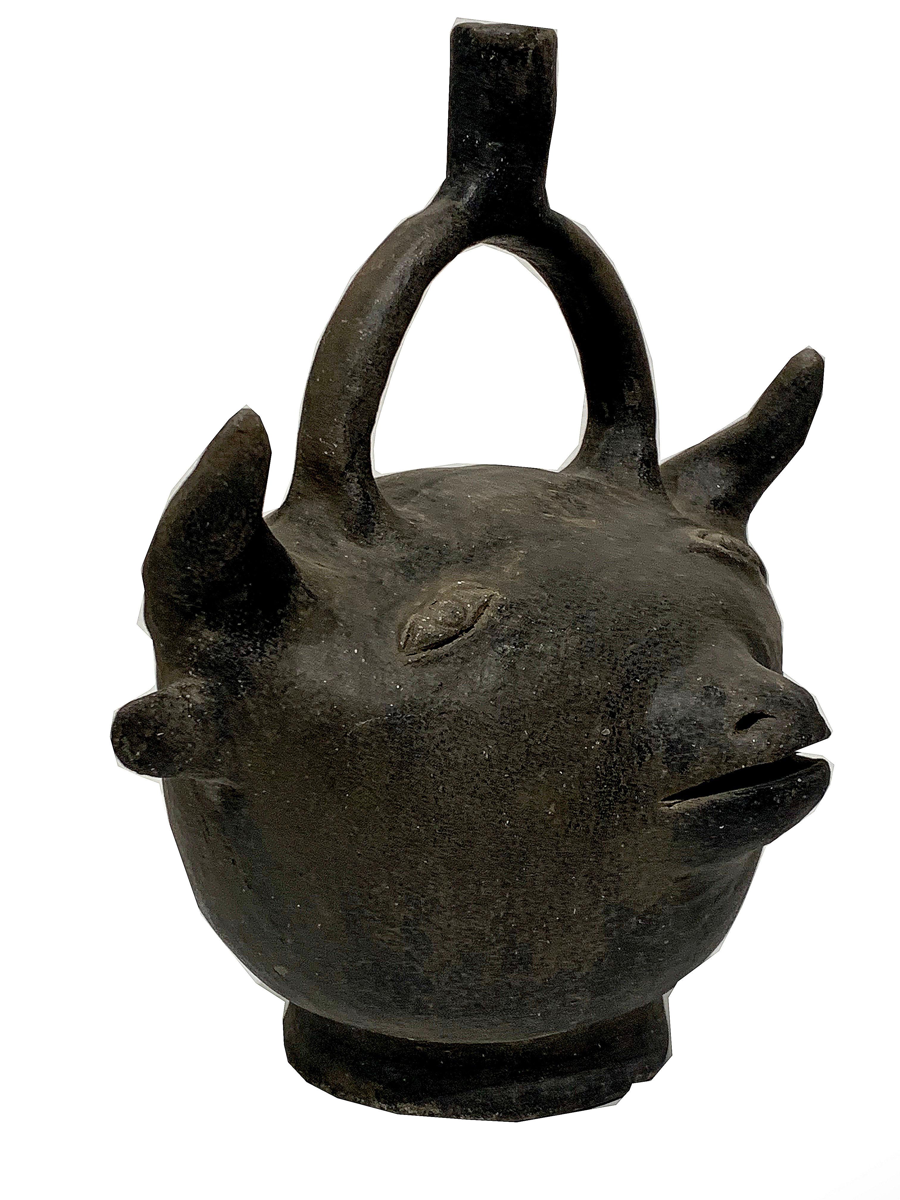 A unique take on a piggy bank, though there is no simple way to remove the coins. With that in mind, we view this as a double faced bull and devil sculpture. Dark brown ceramic, with noticeable variations in color due to age, otherwise in excellent