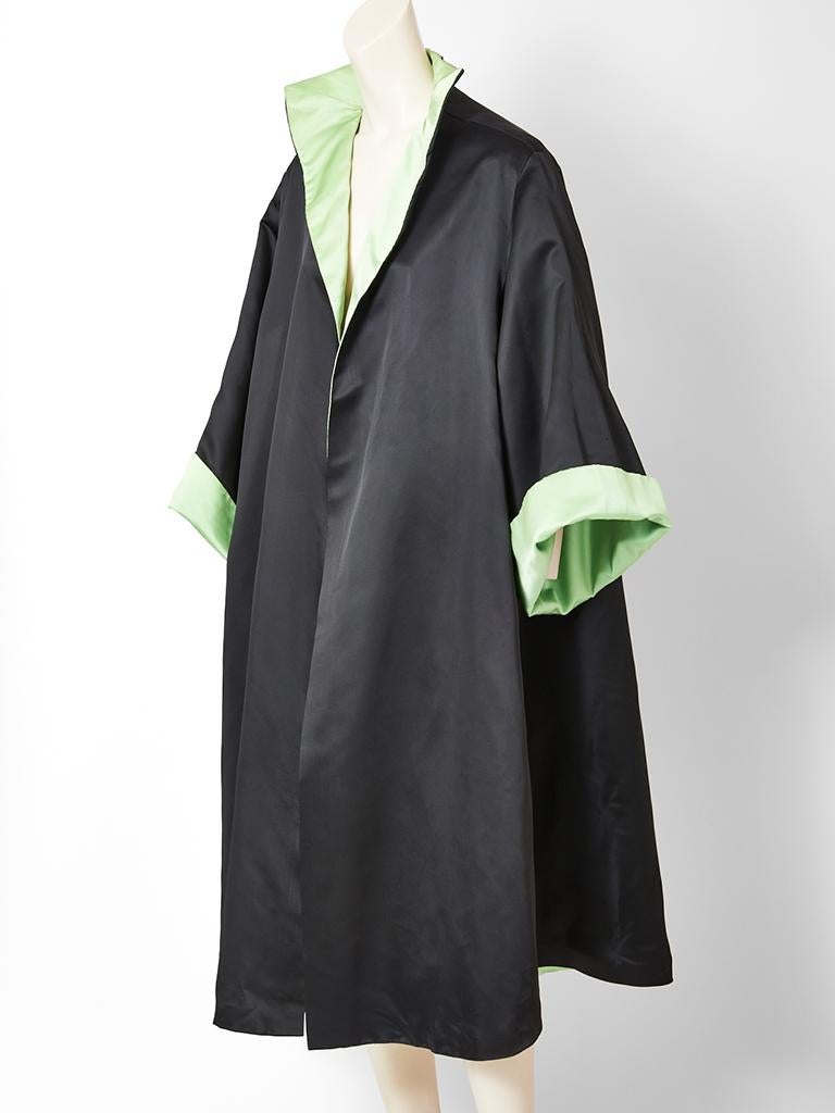 Double face Satin evening coat having a mint green interior and black exterior. Sleeves are raglan with wide cuffs, when rolled up, exposes the mint green lining. Pointed stand up collar with no closures. 
This evening piece was originally bought