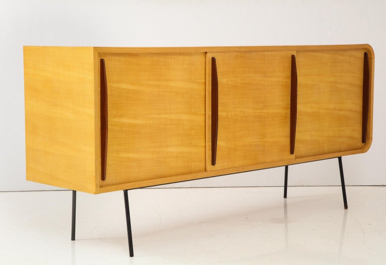 Rare mid-century double-faced credenza by revered furniture designer Raphael Raffel. 

This sleek and stunning credenza consists of sturdy sycamore wood construction with a light blonde grain, tubular steel legs, and three sliding doors on each side
