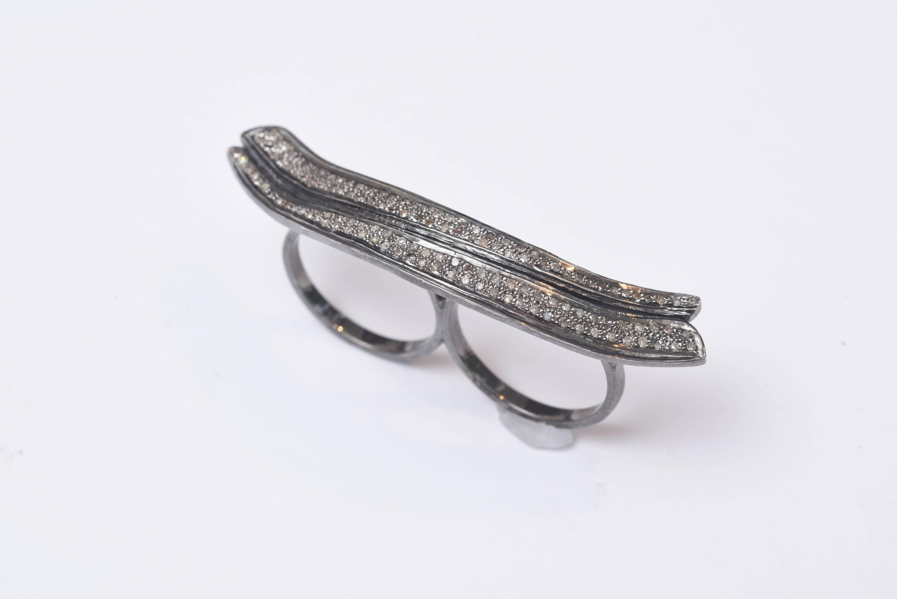 A double finger ring with a double wave of pave`-set diamonds.  In curls and undulates across the top of your hand.  A real conversation piece.  The carat weight of the diamonds is 1.71, set in an oxidized sterling silver.  The two ring sizes are