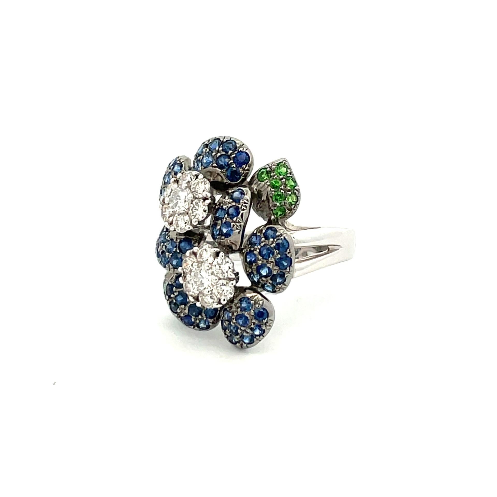 Blooming with sophistication this flower pave ring with natural blue sapphires, natural white diamonds and green garnet in 18kt white gold.

59 natural blue sapphires 1.70ct total weight

11 natural green garnets  .23ct total weight

16 brilliant