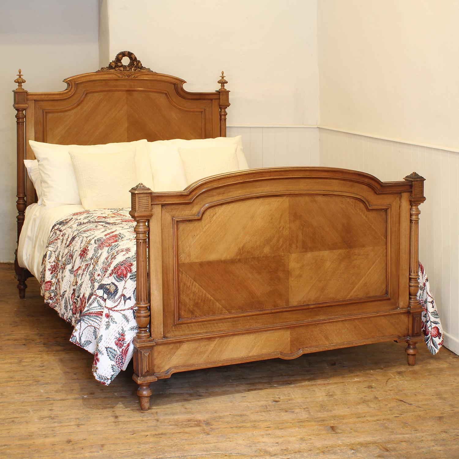 An attractive French walnut bedstead with quartered veneer panels, decorative pediment depicting a garland of roses, carved finials and fluted posts.

This bed accepts a standard double, 4ft 6in (54 in), base and mattress set.

The price is for