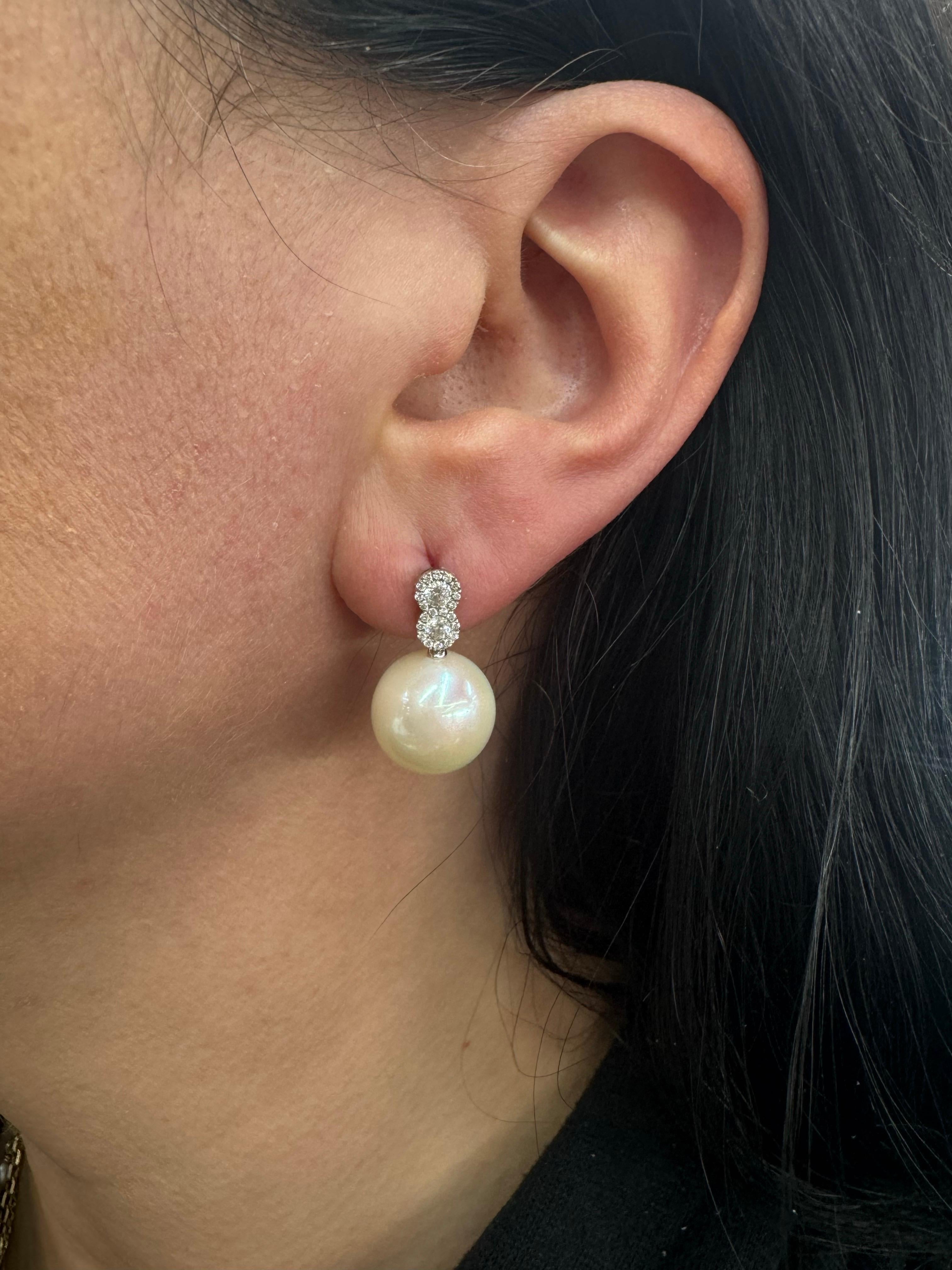 18 Karat white gold drop earrings featuring a double halo design surrounded by 4 round brilliants weighing a total of 0.32 carats and two Freshwater Pearls 12-13 MM. 
