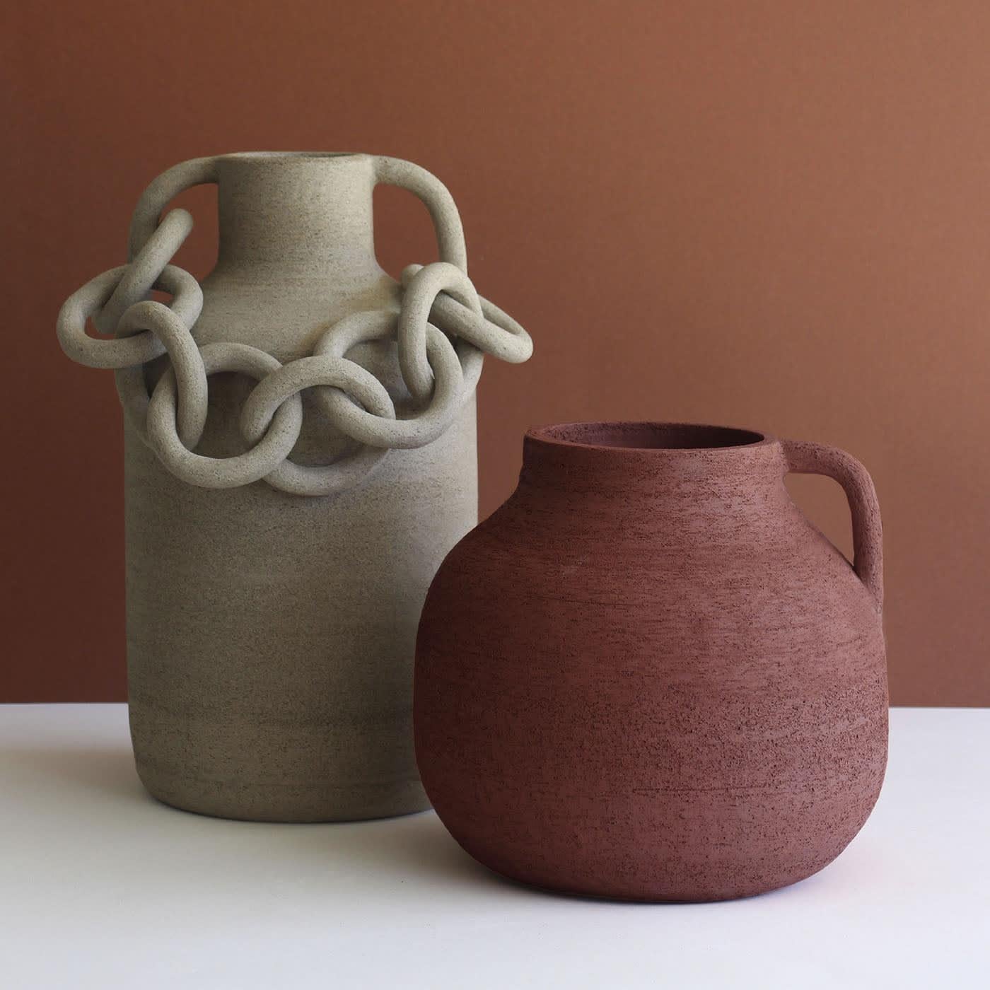 Rings gathered in a chain adorn this precious artisan amphora, a decorative piece fashioned of stoneware and here offered in a sophisticated scratched sand-toned look. The patient and careful manual crafting process ensures the absolute uniqueness
