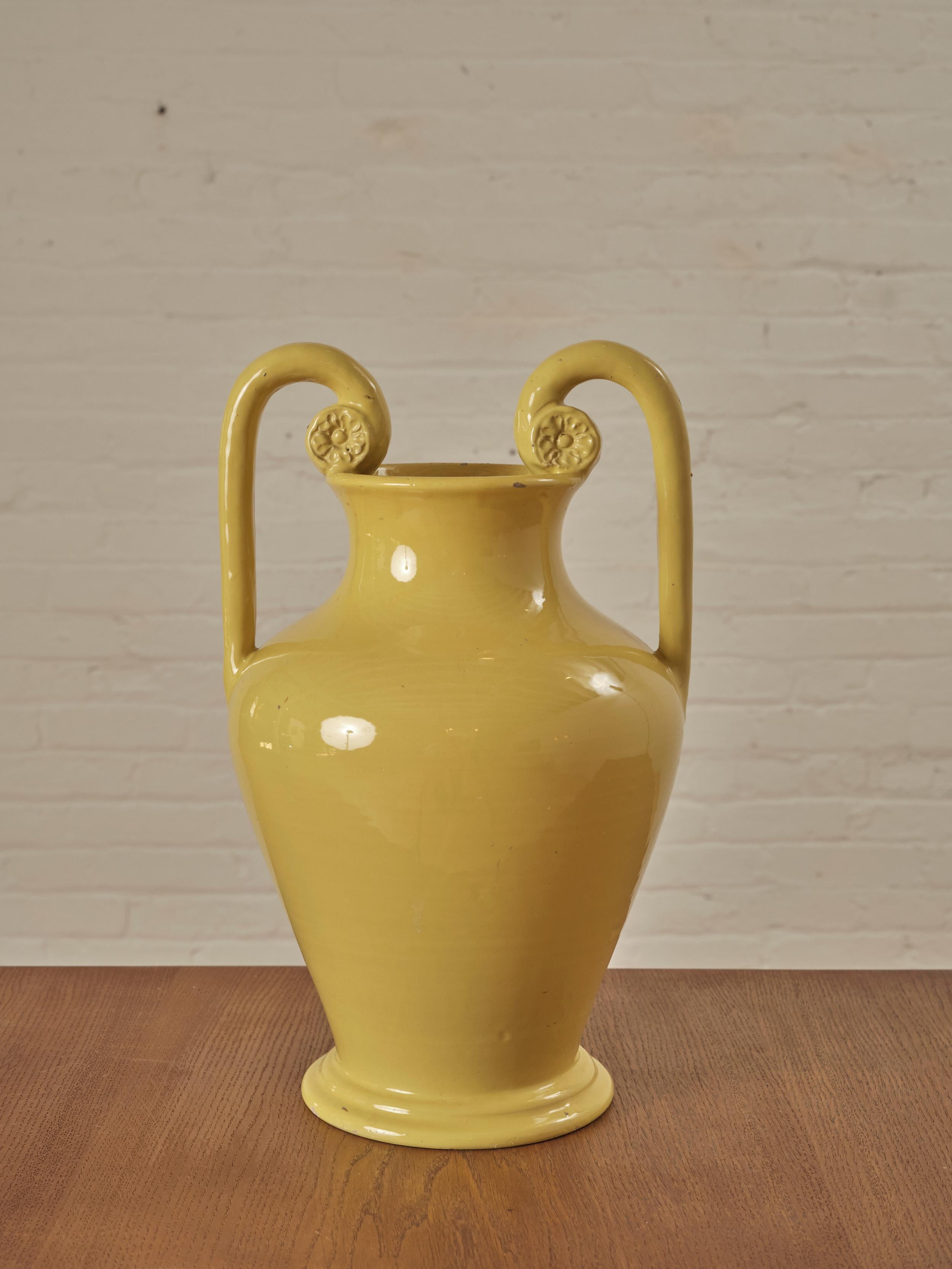 Italian Ceramic Vase with a mustard glaze, features two gracefully curved handles. With its medium-sized stature, this vase can be showcased as a standalone decorative piece or filled with flowers.

