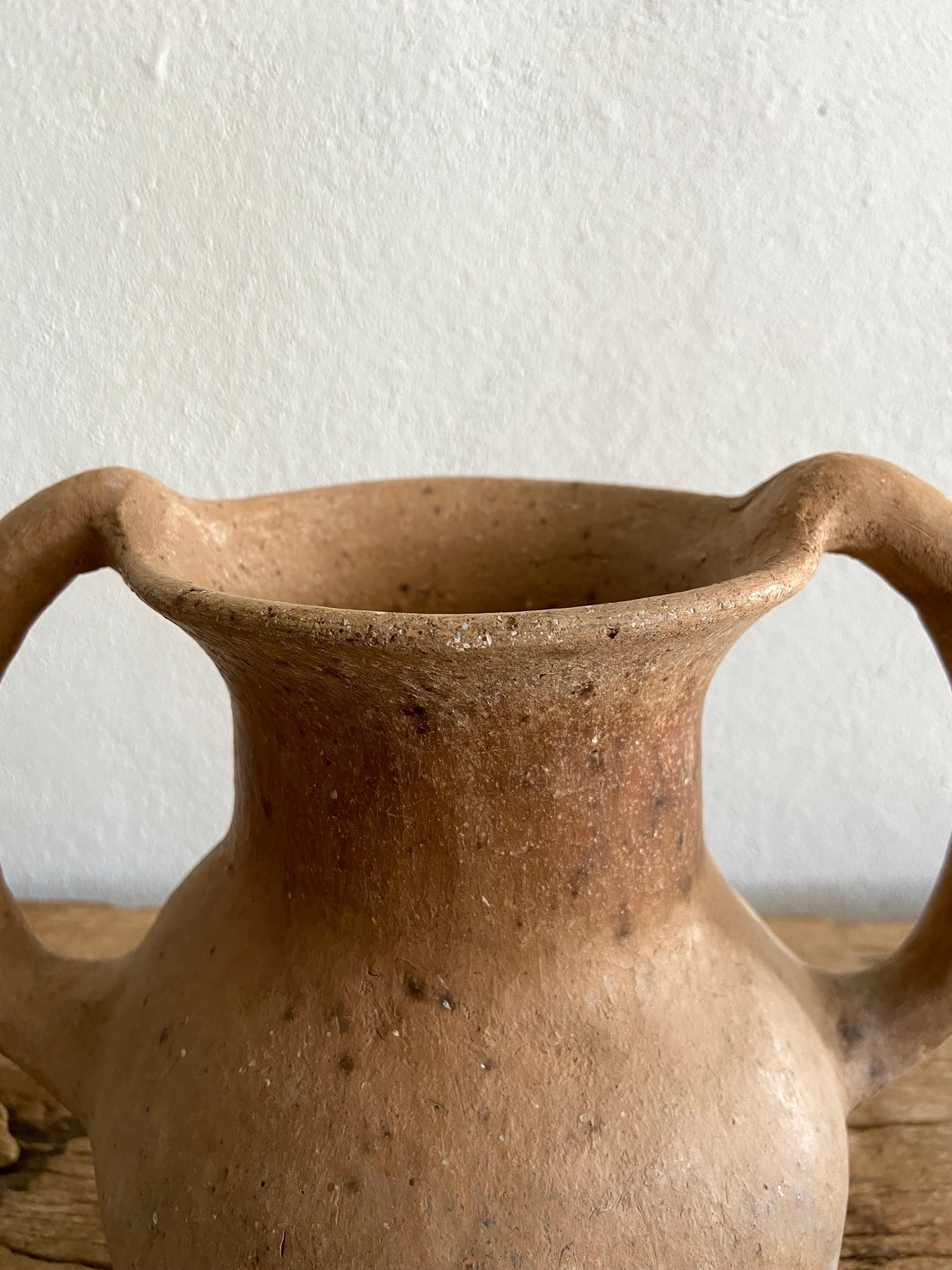 Terracotta water vessel with a double handles from the northern Sierra of Puebla, circa mid 20th century. This vessel was primarily used as a ladle before the introduction of plastics to scoop up water from a larger pot. Plastics didn't reach the