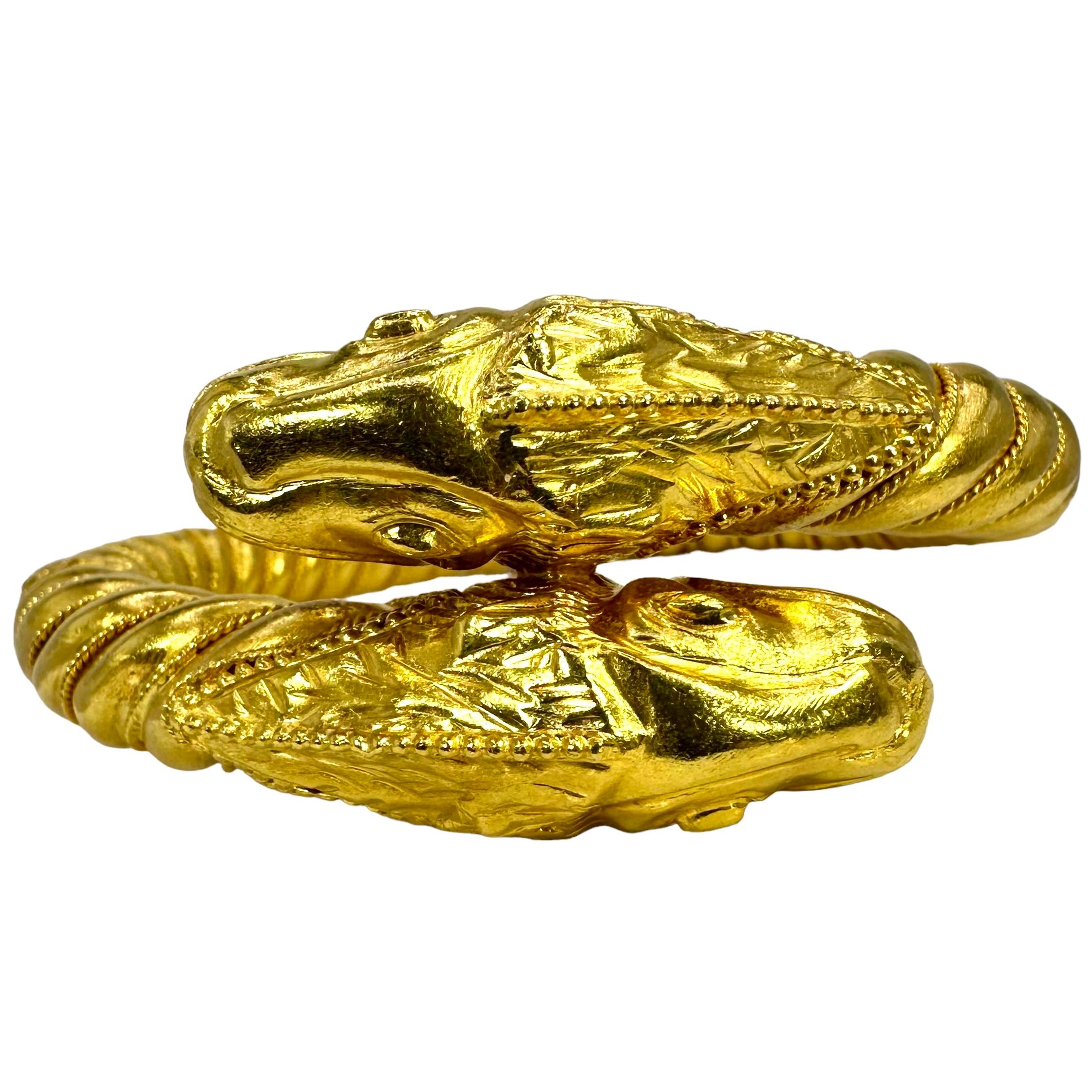 Crafted in 22K yellow gold by Greek designer Ilias Lalaounis, this handsome two headed mythical creature bypass bracelet stands apart from the others. Two oversized heads, facing opposite directions, taper down artistically to connect with the rope