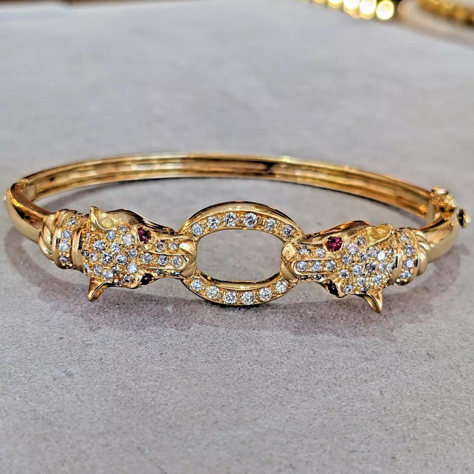 Bracelet panthère à deux têtes avec diamants en or jaune 18k

Le bracelet à tête de panthère présente deux têtes de panthère tenant un anneau ovale orné de diamants ronds de taille brillant et d'yeux en pierre rouge, le tout serti dans de l'or jaune